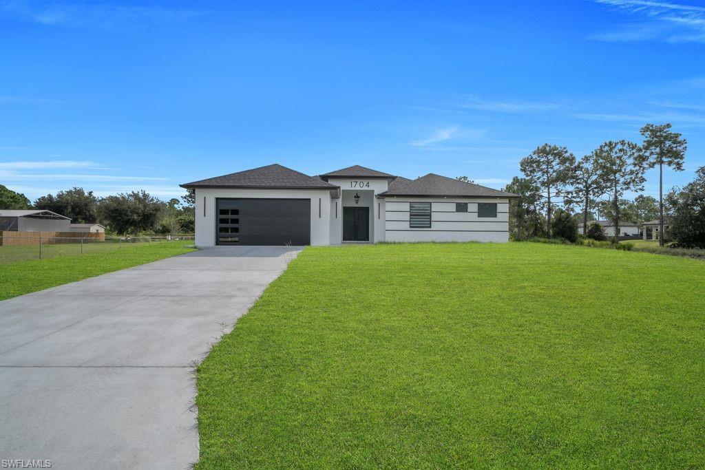 Discover modern living in this brand-new 4-bedroom, 2.5-bathroom home in Lehigh Acres! Offering approximately 2,062 sq. ft. of living space on an oversized half-acre lot, this property combines comfort, style, and room to enjoy. The thoughtfully designed split-bedroom floor plan features vaulted and coffered ceilings, tile flooring throughout, and a spacious living and dining area. The kitchen comes equipped with a pantry, refrigerator, range, microwave, and dishwasher. The primary suite features a private bathroom with dual sinks and a walk-in shower. Additional highlights include impact-resistant windows and doors, a dedicated laundry area, and an attached 2-car garage. With plenty of outdoor space and no HOA fees, this new construction home offers an excellent opportunity to enjoy privacy and modern convenience. Don't miss your chance to make this beautiful property your own!