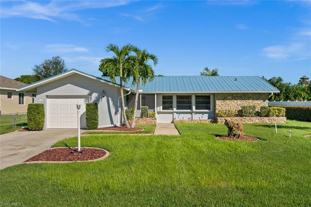 Immaculately maintained and full of classic Florida charm, this inviting home in Southeast Cape Coral offers an exceptional opportunity in an established neighborhood. Featuring 2 bedrooms, 2 bathrooms, and 1,389 square feet of living space, the home has been lovingly cared for and showcases beautiful terrazzo flooring throughout, adding timeless character and durability. The floor plan offers flexible living and dining areas, while an enclosed patio serves as a spacious sunroom. The home's excellent condition reflects years of attentive care, while significant improvements include a durable metal roof installed in 2023, accordion hurricane shutters for added storm protection, new hot water heater, central vac system, luxury plank flooring in entry and kitchen, 2023 freshly painted exterior, Interior including garage and all ceilings.  The spacious yard offers plenty of room for gardening, outdoor activities, or creating your own private outdoor retreat, while a separately fenced side yard provides a convenient, secure area for pets to enjoy. A one-car garage provides convenient covered parking and additional storage. Ideally situated in an established Southeast Cape Coral neighborhood, the property enjoys a convenient location near Cape Coral Parkway, with easy access to the restaurants, shopping, and entertainment of the vibrant South Cape district. Nearby Veterans Park offers outdoor recreation, while convenient access to the Cape Coral Bridge makes traveling into Fort Myers a breeze. Whether you're searching for a seasonal retreat or a comfortable year-round residence, this exceptionally well-kept home offers classic Florida character in a desirable, convenient location.