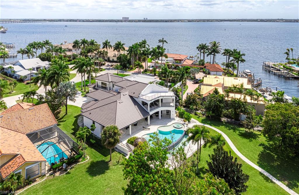 A DISTINCTIVE GULF-ACCESS WATERFRONT ESTATE WITH EUROPEAN DESIGNER INTERIORS ON AN EXPANSIVE 0.58-ACRE LOT! Discover an exceptional combination of waterfront living, generous space, privacy, and sophisticated European design at 4944 Normandy Court. Situated on an oversized 25,221-square-foot property along intersecting canals, this impressive Cape Coral residence offers desirable southwestern exposure, beautiful sunset views, and direct sailboat access to the Gulf with no bridges. Offering approximately 4,915 square feet of living space, the elegant two-story home features 4 bedrooms plus a den, 4 full bathrooms, 2 half bathrooms, soaring ceilings, and expansive, light-filled living areas. A dramatic foyer welcomes you into a residence distinguished by contemporary architecture, an impressive European-designed staircase, and carefully selected designer furnishings from Italy and Switzerland. EUROPEAN DESIGN & SOPHISTICATED INTERIORS set this property apart. The stunning Italian-designed PEDINI kitchen features sleek contemporary cabinetry, elegant black granite countertops, and premium MIELE appliances. The living areas showcase distinctive European furnishings, including a MINOTTI coffee table from Italy, a luxurious DE SEDE sofa from Switzerland in the entertainment lounge, B&B ITALIA beds in the primary and guest suites, and Swiss-designed office furniture. A separate entertainment lounge with billiards and a wet bar creates an inviting setting for entertaining family and friends. OUTDOOR LIVING TAKES CENTER STAGE with a resort-style pool and spa, outdoor kitchen, covered entertaining and dining areas, two tiki huts, expansive terraces, and multiple balconies, including a rooftop terrace offering panoramic views and spectacular Southwest Florida sunsets. The private dock and boat lift complement the property's direct Gulf-access waterfront setting, making it especially appealing to boating enthusiasts. SIGNIFICANT RECENT IMPROVEMENTS provide additional value and peace of mind, including a NEW ROOF IN 2025, multiple A/C system replacements in 2020, 2021, 2024, and 2025, a NEW WATER HEATER IN 2026, newly sealed, paved, and painted balconies, partially upgraded concrete driveway areas, and refreshed exterior finishes throughout the house and outdoor living spaces. Additional highlights include solar panels, a private elevator, wheelchair accessibility, a security system, a safe, and a spacious three-car garage. Offered TURNKEY FURNISHED, this distinctive waterfront residence combines European designer interiors, exceptional indoor-outdoor living, generous privacy, and the freedom of direct Gulf access without bridges. AN EXTRAORDINARY OPPORTUNITY TO EXPERIENCE THE SOUTHWEST FLORIDA WATERFRONT LIFESTYLE, WITH A MOTIVATED SELLER READY TO CONSIDER SERIOUS OFFERS. Schedule your private showing today!