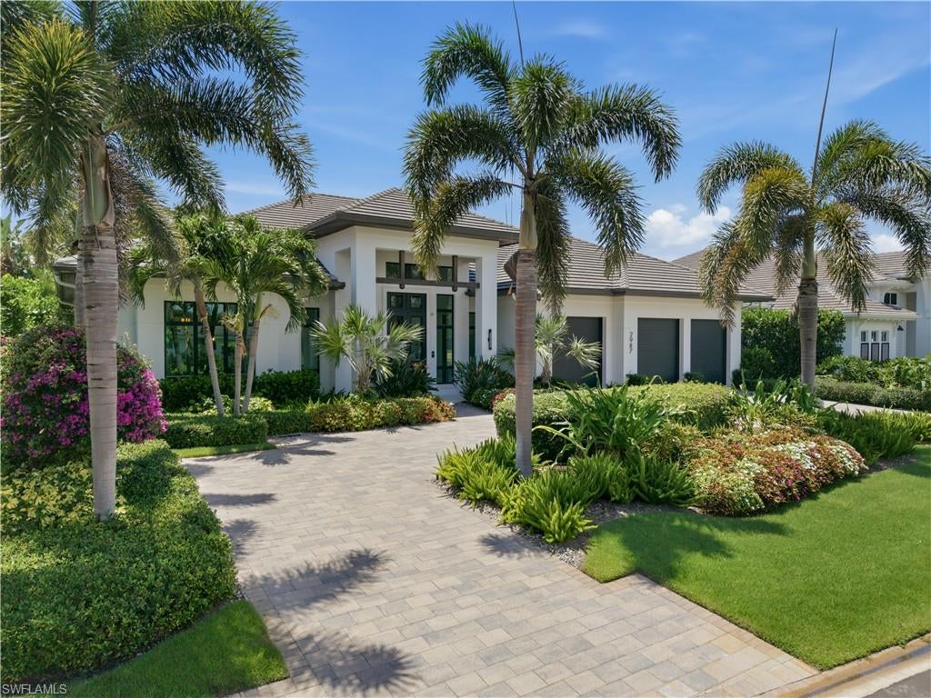 Positioned in one of Naples' most sought-after luxury neighborhoods, this exceptional custom residence on Regatta Road exemplifies timeless architecture, superior craftsmanship, and refined coastal living. Built in 2021 by KKG Luxury Homes, the home offers an impressive blend of elegant design, luxury ceiling details, premium finishes, and state-of-the-art technology throughout. Designed for both everyday comfort and effortless entertaining, the residence features five spacious en-suite bedrooms plus a powder bath, including a generous fifth-bedroom suite that serves as an ideal secondary primary retreat. Legno Bastone wide-plank French oak flooring extends throughout, complemented by Andersen impact windows, automated shades in select rooms, and prewiring for electric shades at every window. The gourmet kitchen is beautifully appointed with Ruffino cabinetry, Cristallo quartzite countertops and full-height backsplash, dual Wolf ovens including a steam oven and microwave, a Wolf six-burner gas range, Sub-Zero refrigerator, and Bosch dishwasher. A separate butler's pantry with an additional refrigerator and dishwasher provides exceptional convenience, while a custom bar with wine cooler and dual refrigerator drawers creates the perfect setting for entertaining. The luxurious primary suite offers a custom walk-in closet with built-ins and a spa-inspired bath featuring a soaking tub and spacious walk-in shower. A custom office provides an elegant and functional work-from-home space. The expansive outdoor living area is designed for year-round enjoyment with a covered lanai featuring a fireplace, electric screens and shutters, shell stone flooring, and a fully equipped outdoor kitchen with grill, refrigerator, and ice maker. The saltwater pool and spa are surrounded by lush tropical landscaping, enhanced landscape lighting, a private backyard, and an outdoor shower. Front exterior lighting is integrated into the pool automation system for convenient control. Additional luxury features include Sonos audio, Lutron lighting, a Control4 smart home system, a 1,000-gallon propane tank, whole-house generator, two tankless water heaters, dual air-conditioning systems, and a three-car garage with custom slat wall storage. Residents of The Moorings are eligible for voluntary membership to the private Moorings Beach Park, offering exclusive beach access and amenities (subject to availability and membership approval). This exceptional residence presents a rare opportunity to enjoy luxury living in one of Naples' premier waterfront communities.