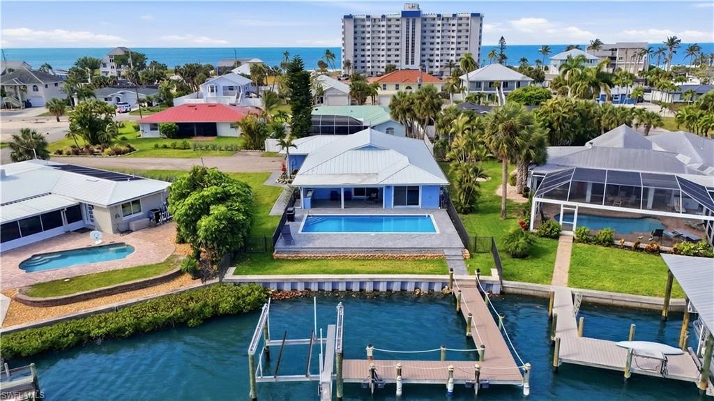 Completely reimagined waterfront residence in Laguna Shores overlooking tranquil lagoon waters with direct Gulf access. Completely remodeled (2024–2025), this fully permitted renovation delivers true peace of mind with all-new systems, finishes, and structural upgrades throughout. The interior features porcelain woodgrain tile flooring, quartz countertops throughout, custom cabinetry, and a designer kitchen with oversized island and high-end Samsung Bespoke appliances. Tray ceilings elevate the main living areas and primary suite, while the spa-inspired primary bath includes an infrared sauna and steam shower for a true retreat experience. Major upgrades include a new standing seam metal roof, impact-rated windows and doors (Miami-Dade code), new electrical with panels and wiring, new plumbing, and elevated HVAC systems with tankless water heater. StormSmart motorized lanai screens create seamless indoor-outdoor living. Outdoor spaces have been completely transformed with a resurfaced pool, new pavers, outdoor kitchen, pool shower, and updated native landscaping. The waterfront has been enhanced with a new seawall, concrete cap, tie-backs, rip rap, and a renovated dock with 10,000 lbs boat lift. Additional features include hurricane-rated garage door, irrigation system, well, security system, flood protection panels, and more. Ideally located on the south end of Fort Myers Beach near dining, shopping, and beach access, this is a rare opportunity to own a fully rebuilt, move in ready waterfront home in one of the island’s most desirable boating communities.