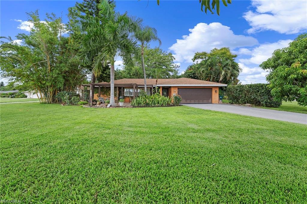On an oversized 0.41-acre corner lot amid lush, mature landscaping, this Mediterranean-style residence in Greenwood at Palm River Estates offers a distinctive expression of indoor-outdoor living in North Naples. Built in 1974 and offering 2,131 square feet with four bedrooms and two baths, the home unfolds through a series of connected gathering spaces designed for conversation, dining and entertaining. Terrazzo floors lend character throughout the main living areas, where a dedicated bar creates a natural gathering point and the dining area flows into a well-equipped kitchen. Granite countertops, wood cabinetry, stainless steel appliances and a substantial gas range support everything from everyday meals to evenings shared around the table. Gas service is supplied by a 120-gallon propane tank. The home's personality continues outdoors. Impact-resistant sliding doors open to an expansive, screen-enclosed lanai where a built-in pizza oven imported from Italy becomes a centerpiece for alfresco dining. Beyond, paver surfaces wind through mature tropical landscaping and fruit trees to a courtyard-style setting with a pergola-style structure and decorative fountain. Together, these outdoor spaces create inviting places for morning coffee, dinner beneath the lanai or an evening gathered around the pizza oven. Plantation shutters, recessed lighting, a newer roof (2023) and a two-car garage add to the home's features. Greenwood is an intimate enclave of just 25 low-maintenance residences within established Palm River Estates, with landscaping included in homeowners association services. Community amenities include a renovated community room, park, sidewalks, and a new heated community pool and spa expected to open soon. From its Italian pizza oven and garden spaces to its terrazzo floors and interconnected living areas, 511 Eastwood Drive offers a home with individual character and room to gather, all from an established North Naples location convenient to Gulf beaches, shopping, dining and recreation.