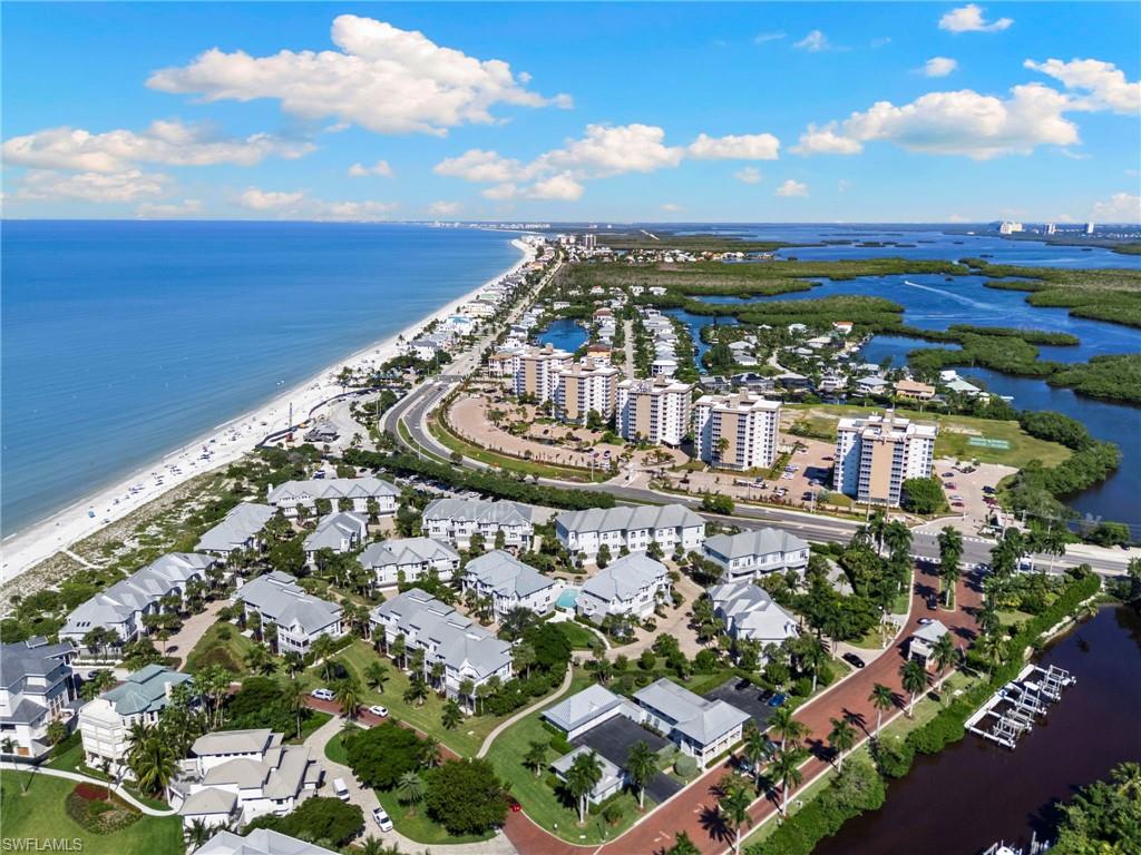BAREFOOT BEACH VILLAS | LUXURIOUS FINISHES | ELEVATED COASTAL LIVING. Discover exceptional coastal luxury in the gated Villas at Barefoot Beach. This beautifully appointed, recently fully renovated three-story end-unit residence offers approximately 2,800 square feet, 3 bedrooms, 3.5 bathrooms, a private elevator, and a two-car garage, just moments from the Gulf of Mexico.

Sophisticated architectural details include soaring ceilings, elegant millwork, wide-plank wood flooring, plantation shutters, oversized arched windows, designer lighting, and a striking staircase with glass railings, brushed-metal accents, and natural wood treads. The expansive great room features an illuminated tray ceiling and flows seamlessly into the dining area and gourmet kitchen.

A spectacular large kitchen island with dramatic stone-look countertops sits beneath a multi-tiered uniquely lit crystal chandelier. Custom two-tone cabinetry, turquoise tile backsplash, Miele and Wolf appliances, double ovens, electric cooktop, wine cooler, and abundant storage complete the space. The adjacent dining area features another crystal chandelier and floor-to-ceiling glass-front cabinetry with display lighting. An impressive glass-enclosed 90+ bottle wine wall at the upper landing provides an additional luxury statement.

The elegant primary suite features wood flooring, illuminated tray ceilings, plantation shutters, and abundant natural light. Its spa-inspired bathroom showcases a frameless glass shower, freestanding soaking tub, floating dual-sink vanity, contemporary fixtures, LED-illuminated mirrors, and decorative wall finishes. An extraordinary custom dressing room features extensive built-in cabinetry, glass-front storage, a dedicated coffee and beverage station, and infrared sauna.

Guest bedrooms offer refined finishes and plantation shutters, while guest bathrooms feature frameless glass showers, custom vanities, designer tilework, and illuminated mirrors. A Murphy bed provides flexibility for guests or additional living space.

Private balconies and terraces overlook lush tropical landscaping and charming brick-paver streets. Additional conveniences include a private elevator, spacious two-car garage with overhead storage, and extensive custom cabinetry.

Villas at Barefoot Beach is an intimate gated community of just 50 residences featuring 2 swimming pools, spa, tropical landscaping, and 200 yards to beach access. Ideally located near Barefoot Beach Preserve, waterfront dining, boating, and the upscale shopping and entertainment destinations of Naples and Bonita Springs. Experience exceptional craftsmanship, sophisticated design, and the extraordinary Barefoot Beach lifestyle.