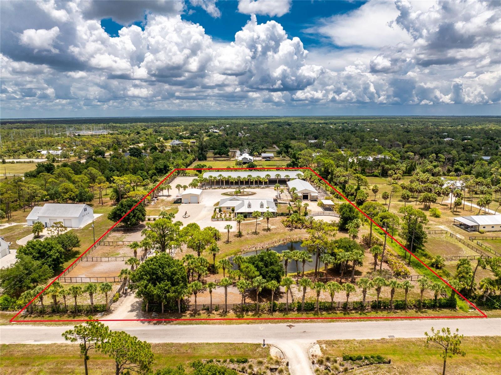 Premier 5 Acre Equestrian Estate in Englewood Farm Acres with Covered Arena and 11 Stall Barn! This exceptional property offers outstanding equestrian amenities, including an 11 stall center aisle barn, covered and outdoor riding arenas with engineered arena footing and drainage, 7 paddocks, and extensive equestrian infrastructure, all within easy reach of Florida's premier show venues. The 4 bedroom, 3.5 bathroom home features a split floor plan with hardwood flooring in the foyer, great room, kitchen, dining room, and primary bedroom, an intercom system, and French doors leading to the screened lanai from both the great room and primary suite. The kitchen has white cabinetry, breakfast bar, and dual pantries, and the formal dining room features a bay window. The primary suite includes dual walk-in closets, tray ceiling, private lanai access, and an ensuite bathroom with dual split vanities, and walk-in tiled shower. The private guest wing with separate entrance includes the 4th bedroom, bathroom, wet bar, bonus room, and screened patio. Recent improvements include a June 2026 HVAC, attic fan, UV light, a heated saltwater pool and spa, and a Generac generator servicing all buildings on the property. Outside, the gated estate includes a circular driveway, landscaping, pond, fenced pastures, RV/ boat parking, an attached three car garage, a detached 30x40 shop, 30 amp and 50 amp hookups, and an outdoor built-in grill. The impressive 96x40 center aisle barn includes eleven 12x12 MD Barn stalls with 12x24 run ins, Nelson automatic waterers with water intake monitoring, Nelson feeders, stall mats, individual fan and light controls at every stall, two grooming stalls with individual fans, permeable rubber pavers and drains, a laundry station with 220 service, tack cleaning sink, and a 12x36 tack room + office with bathroom, spray foam insulation, A/C, travertine flooring, granite countertops, and an electrical closet with wiring for cameras and the arena sound system. There is also a 66x200 outdoor arena featuring an elevated viewing station attached to the shop, automatic sprinklers, and a 2% grade for drainage, an 80x220 covered arena with 80 foot mirrors, automatic sprinklers at the mirrored end, fresh paint completed in 2025, a 2% grade from the center, GGT Premier footing with masonry sand over a 99% compacted six inch bank run shell base, two covered wash racks with crossties, seven paddocks serviced by a dedicated 5HP well with automatic waterers, hose bibs, and shut offs at each paddock, drainage throughout the property including underground drainage, a 20 inch drainage pipe, concrete culverts, and graded arena surfaces designed to direct water away from the riding areas, dual electrical panels serving the home and barn, electrical power, USB, fiber optic service, future conduit throughout the property, and the ability to supply the barn with either well or city water. Ideally located approximately 30 minutes from Fox Lea Farm in Venice, 1-hour from TerraNova, and approximately 3-hours from White Fences Loxahatchee, Global Dressage Wellington, and the World Equestrian Center, this exceptional estate at 668 Palomino Trail in Englewood, FL combines luxury living with outstanding equestrian amenities and puts you just minutes from Gulf beaches, boating, and historic Dearborn Street.