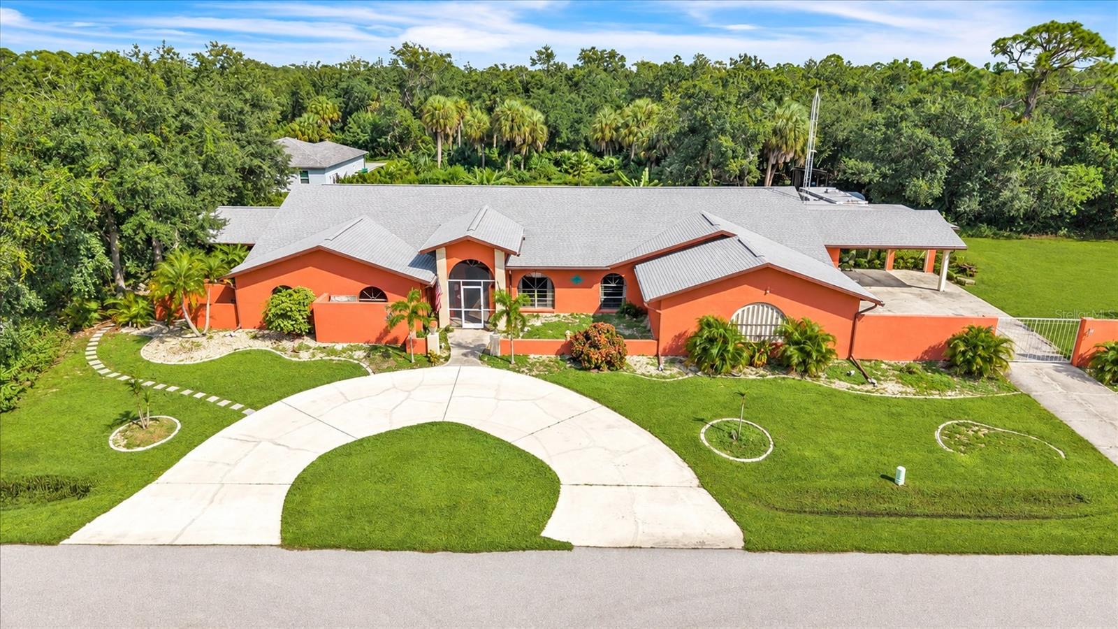 FIVE LOTS TOTALING APPROXIMATELY 1.15 ACRES. 5,178 SQUARE FEET UNDER AIR. A TROPICAL POOL RETREAT AND A PRIVATE GUEST SUITE! Spread out, entertain, and explore the possibilities in this expansive Port Charlotte estate featuring 4 BEDROOMS, 5.5 BATHROOMS, 2 BONUS ROOMS and exceptional spaces for gathering, working, and relaxing. From the approximately 1,000 square foot ENTERTAINMENT ROOM to the sprawling fenced backyard, this property offers room to enjoy life on a larger scale. Mature trees, tropical landscaping, a distinctive coral exterior, and a sweeping circular driveway create a memorable welcome. A separate driveway leads to the garage and covered parking, while a NEW ROOF IN 2023 adds to the appeal. Inside, the OPEN CONCEPT GREAT ROOM combines spacious living and dining areas with distinctive architectural details. Overlooking the pool, the kitchen features GRANITE COUNTERTOPS, SOLID WOOD CABINETRY, and generous preparation space. An OVERSIZED WALK IN PANTRY ROOM offers white shaker style cabinetry, additional countertops, shelving, and storage racks. A separate laundry room adds convenience. The PRIMARY SUITE offers a private sitting area, TWO WALK IN CLOSETS, and an ensuite bathroom with a soaking tub, walk in shower, and dual sink vanity. An adjoining bonus room, currently a playroom, provides flexible space for hobbies, exercise, or relaxation. Two guest bedrooms occupy the opposite side of the home, near a half bathroom and a full bathroom with a walk in shower. An additional bonus room, currently a craft room, offers space for creative projects or a home office. BRING ON THE GATHERINGS! The approximately 1,000 square foot ENTERTAINMENT ROOM features tile flooring, decorative ceiling details, generous seating and dining space, and DIRECT POOL ACCESS. A custom bar with countertop seating, wood accents, and display shelving anchors the space, while an adjoining kitchenette includes cabinetry, countertops, and a sink. This entertainment room also offers potential for use as an additional bedroom or in law suite. On the left side of the residence, the PRIVATE GUEST/IN-LAW SUITE provides its own BEDROOM, FULL BATHROOM, FULL KITCHEN, LIVING AREA, PRIVATE LANAI and POOL ACCESS, ideal for MULTIGENERATIONAL LIVING or extended guest stays. Previously used as an Airbnb, this space also presents potential rental opportunities. Outside, the EXPANSIVE SCREENED LANAI offers plenty of space for poolside dining and relaxation. A decorative ROCK WATERFALL, tropical landscaping, and recently repainted pool deck surround the swimming pool. A full bathroom accessible from the pool area adds convenience. Colorful landscape lighting and illuminated water features create a beautiful evening atmosphere. Beyond the lanai, the FENCED BACKYARD offers an expansive lawn, mature shade trees, and room for gardening and recreation. A 25' X 30' ATTACHED GARAGE, TWO CAR CARPORT, and SHED/WORKSHOP provide substantial space for vehicles, equipment, storage, and projects. An approximately 7 acre county owned park sits directly across the street, adding to the open surroundings. Conveniently located near shopping, dining, medical facilities, boating, fishing, and Gulf Coast beaches, this distinctive property combines space, versatility, and a memorable tropical setting. Schedule your private showing and discover the possibilities!