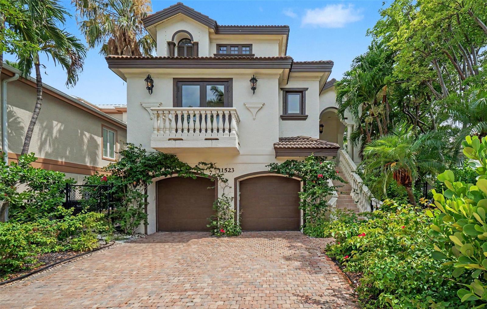 Virtually Staged. Virtually Staged. Welcome to one of Captiva Island's most remarkable residences: a stunning Mediterranean-inspired estate nestled on the legendary Andy Rosse Lane, just steps from the Gulf of Mexico. Move-in ready and finished with fine stylings throughout, this multi-level home delivers the perfect blend of luxury island living, flexible accommodations, and exceptional investment potential as a short-term rental.  Arrive via a classic paver brick driveway framed by lush tropical landscaping, climbing vines, and colorful blooms. The stucco façade, clay tile roofline, arched garage doors, and elegant balustrade balcony set a tone of timeless sophistication from the moment you pull in. A grand staircase sweeps up to the main entry, while a private elevator services every floor of the main house for effortless access. The ground level features a spacious two-car garage with ample storage, a large recreation room perfect for a game room, media lounge, or fitness space, and a full en suite bathroom, ideal for guests or extended stays without ever needing the upper floors. The heart of the home unfolds across a sweeping, light-filled main level featuring large-format travertine tile, soaring coffered ceilings, and graceful arched doorways. Dual chandeliers anchor a dramatic tray ceiling above the open-concept living and dining room, a space bathed in natural light through picture windows and French doors that open to the outdoors. The gourmet kitchen is a chef's dream, offering custom white cabinetry, a generous island with breakfast bar seating, a walk-in pantry, and a bold statement range hood that adds a touch of artful color. Two well-appointed guest bedrooms, each with a private en suite bathroom, provide comfort and privacy for family and visitors alike. The main level is rounded out by a convenient laundry room and a powder half bath for guests. The entire top floor exemplifies refined luxury. The primary suite is a true sanctuary, featuring two expansive walk-in closets and a spa-caliber bathroom that will take your breath away. A dramatic black clawfoot soaking tub with polished chrome fixtures rests beneath a crystal chandelier, flanked by a dual-sink vanity with backlit mirrors, a rich marble tile surround, and a separate oversized walk-in shower. Glimpses of the tropical landscape through the primary bath's windows complete this private retreat. A fourth bedroom with its own en suite bath completes the top floor, perfect for a home office, nursery, or additional guest quarters. A covered balcony walkway connects the main house to a fully independent in-law suite, a rare and coveted feature on Captiva Island. This self-contained retreat includes a private bedroom, full bathroom, and kitchenette, making it perfect for extended family, a live-in property manager, or a dedicated short-term rental unit. Directly below the in-law suite, a pool bath and bonus room offer additional flexibility for outdoor entertaining, equipment storage, or a cabana-style hangout. Situated on Andy Rosse Lane, Captiva's beloved main street,  this home places you at the center of island life. Stroll to the Gulf beach in seconds, or walk to iconic local favorites like the Mucky Duck and the Bubble Room. Whether you're seeking a full-time residence, a personal island getaway, or a high-performing vacation rental, 11523 Andy Rosse Lane checks every box. Properties of this caliber, in this location, rarely come to market. Schedule your private showing today.