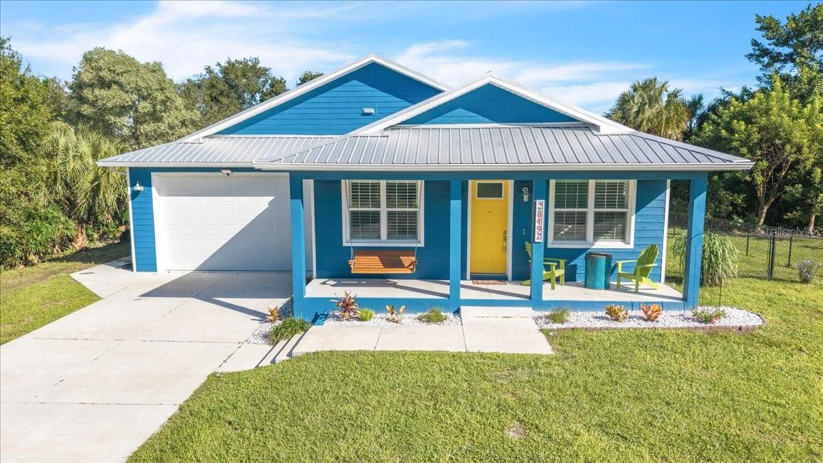 Key West-inspired waterfront retreat with direct sailboat access, new dock and boat lift (2025), and 80 feet of concrete seawall! Discover this exceptional fully furnished, custom-built 2023 home featuring 3 bedrooms, 2 bathrooms, a private office, and an oversized 2-car garage in the waterfront community of Palm Shores in Punta Gorda! Designed with creativity and attention to detail, this distinctive residence blends modern construction with vibrant coastal character. A striking blue exterior, cheerful yellow front door, and tropical landscaping create memorable curb appeal. Inside, the bright, open-concept floor plan showcases white shiplap walls, light-toned plank-style flooring throughout, and soaring vaulted ceilings. Recessed lighting, decorative fixtures, plantation shutters, and abundant natural light enhance the inviting atmosphere. The spacious great room flows effortlessly into the dining area and kitchen, while expansive pocket sliding glass doors open to the screened lanai, creating an ideal layout for entertaining. The showstopping kitchen features rich blue Shaker-style cabinetry, vibrant orange retro-style Big Chill appliances, a Vetrazzo recycled glass island, and a Fireclay farmhouse sink. A generous breakfast bar provides casual seating, complemented by open display shelving and stylish pendant lighting. The adjoining dining area offers a welcoming space for everyday meals and gatherings. The spacious primary suite offers a peaceful retreat with a decorative ceiling fan and large windows overlooking the surrounding greenery. Its ensuite bathroom features a custom distressed blue wood vanity, rustic wood countertop, white vessel sink, wall-mounted faucet, and oversized wood-framed mirror. The walk-in shower is beautifully finished with blue subway-style tile, pebble-stone flooring, and a window for natural light. Two additional guest bedrooms provide comfortable accommodations, while the guest bathroom showcases a nautical porthole-style mirror, vintage-inspired wall-mounted faucet, white farmhouse-style sink, and walk-in shower with white subway tile. A distressed storage cabinet adds a charming finishing touch. A dedicated home office provides flexibility for remote work or hobbies. Enjoy the outdoors from the spacious screened lanai, featuring colorful Adirondack seating, decorative string lighting, and views of the backyard. A separate wood deck with fire pit creates another inviting gathering space, while the fenced yard offers privacy amid lush tropical surroundings. Boating enthusiasts will appreciate the new dock 2025 and boat lift installed 2026, 80 feet of concrete seawall, and direct sailboat access to the Peace River, with access to Charlotte Harbor and the Gulf of Mexico beyond. Additional highlights include hurricane-impact windows and doors, an approximately 11-foot elevation, and modern building code construction. The oversized 2-car garage features an epoxy-finished floor, a 220V electrical outlet, and generous space for vehicles, storage, or a workshop. With no HOA or association fees, this property offers flexibility for year-round or seasonal enjoyment. Conveniently located near historic downtown Punta Gorda, waterfront parks, shopping, dining, entertainment, and I-75, this home puts Southwest Florida's attractions within easy reach.