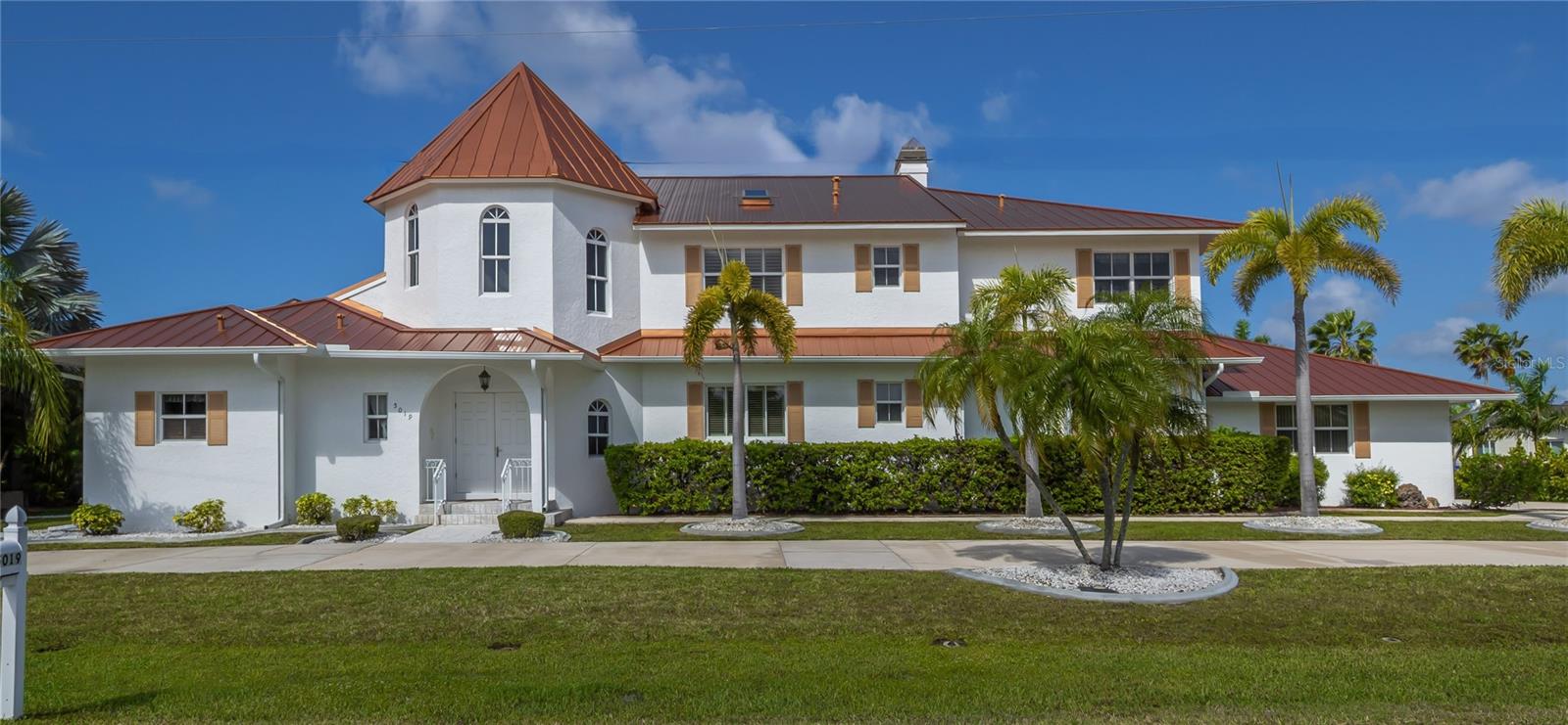 This stunning Mediterranean-style executive estate sits on two premium waterfront lots offering 160 feet of sailboat-access canal frontage — the ultimate setting for the serious boater or coastal lifestyle enthusiast. Located in the sought-after Punta Gorda Isles community, this one-of-a-kind home delivers the perfect blend of Old World elegance and modern Florida waterfront living. Enter through an impressive tower entrance that sets the tone for everything that follows. A beautifully crafted solid oak staircase greets you upon arrival. The heart of the home is a soaring great room with its dramatic ceiling height, walls of windows flooding the space with natural light, and rich oak paneling adding warmth and sophistication. The main sitting area anchors around a classic fireplace — ideal for Florida's cooler evenings — while the open layout accommodates multiple conversation areas perfect for entertaining on any scale. Updated 24-inch tile flows throughout the living areas on the main floor, and a wraparound second-floor balcony overlooks the entire space from above. The well-appointed kitchen features 42-inch wood cabinetry, Corian countertops, stainless steel double refrigerator/freezer, a center island with cook top, built-in desk, and casual dining area.  The adjacent formal dining room is bathed in natural light, framed by handsome wood beam ceilings, and overlooks the pool and waterfront. Built-in corner cabinetry throughout provides generous storage without sacrificing style. The expansive master suite is a private sanctuary. A newly installed private elevator connects the master level directly to the upstairs den, a  convenience rarely found in residential properties. The recently updated master bath showcases white wood cabinetry, dual sinks, a deep soaking tub, and a generous walk-in shower. A large walk-in closet and a separate walk-in linen closet ensure that storage is never a concern. An adjoining air-conditioned flex room — ideal as a home gym, workshop, or creative studio — includes a half bath. Both water heaters replaced 2026. A second bedroom on the main floor near the entry features a custom built-in bed and walk-in closet, served by a beautifully updated bath with wood cabinetry, marble countertops, and a walk-in shower. Upstairs, a third bedroom offers access to a large cedar-lined closet as well as a full bath featuring a tub, tile floors, and quartz countertops. At the end of the upper hallway, a handsome oak-paneled den with fireplace provides a quiet retreat. Rounding out the upper level is a delightful English-style pub complete with built-in bar seating and custom woodwork — great for entertaining and a truly unique feature that sets this property apart from anything else in the area. The screened lanai features a sparkling pool and spa alongside a gallery-style covered passage along the exterior of the great room — an elegant transition between indoors and the waterfront. The double-lot configuration and generous seawall provide ample space to dock the boat of your choice with direct sailboat access to Charlotte Harbor and the Gulf of Mexico beyond. Whether you're a day sailor, offshore angler, or simply love waking up to waterfront views, this property delivers the quintessential Florida boating lifestyle. See this property today! You won't be disappointed!