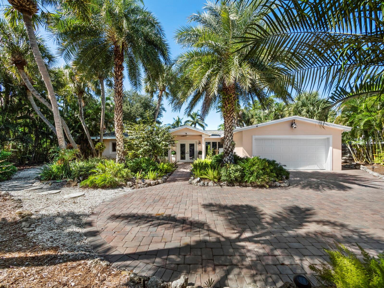 An exceptional opportunity for waterfront living. Discover a private waterfront retreat where boating, tropical gardens, and relaxed island living come together in one of Siesta Key's desirable residential neighborhoods. Set behind a gated entrance and surrounded by lush landscaping, this beautifully refreshed three-bedroom, two-and-a-half-bath residence offers an inviting blend of coastal comfort, privacy, and exceptional outdoor living. Designed to embrace the Florida lifestyle, the spacious, open living and dining areas feature easy-care tile flooring, abundant natural light, and effortless connections to the outdoors. The updated kitchen offers granite countertops, white cabinetry, stainless steel appliances, and a welcoming dining area overlooking the pool and gardens. The comfortable primary suite and two additional bedrooms provide flexibility for family, guests, or a home office. A distinctive Bali-inspired bath with an indoor-outdoor shower adds an unexpected touch of tropical character. The heart of this property is its extraordinary screened outdoor living area. An expansive swimming pool and elevated spa are surrounded by generous paver decking, multiple lounging and dining spaces, and a covered lanai, creating a wonderful setting for entertaining or simply enjoying the island breezes. Beyond the pool, a beautifully landscaped backyard unfolds toward the waterfront, offering a peaceful garden setting with mature palms, tropical foliage, and room to relax. For boating enthusiasts, the private dock and 7,000 lb. boat lift provide convenient access to Sarasota Bay, the Intracoastal Waterway, and the Gulf beyond. Spend the morning cruising the waterways, enjoy an afternoon on the water, or launch a kayak or paddleboard right from your backyard. A welcoming covered entry, gated paver driveway, and attached two-car garage with additional storage complete this distinctive island property. Just minutes from Siesta Beach's renowned quartz-white sands, Siesta Village's restaurants and boutiques, and the cultural attractions of downtown Sarasota, this residence delivers the best of coastal living in a wonderfully private setting. Whether entertaining around the pool, exploring Sarasota's waterways, or simply enjoying the tranquility of your own tropical gardens, this is an opportunity to embrace the Siesta Key lifestyle