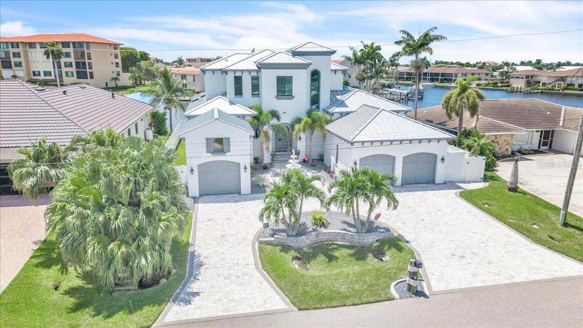 DIRECT SAILBOAT ACCESS, no bridges, from a wide-water lot on a 200-foot canal just 150 yards off the Caloosahatchee. Untie the lines and you are running open water before your coffee cools. Set in the sought-after Savona neighborhood of southeast Cape Coral, this two-story, 5-bedroom, 6-bath residence of approximately 3,600 square feet is built around the view. The outdoor living rivals a private resort: a resurfaced saltwater pool, new travertine decking, a full outdoor kitchen, and a waterfront tiki hut made for long evenings after a day offshore. At the water, a new composite dock deck, a 40-foot slip, a 30,000-lb boat lift, and a Jet Ski lift wait for whatever you keep in the water. Step inside and the scale registers immediately: ~12-foot ceilings on the main level, with luxury maintenance-free LVP flooring throughout. Four bedrooms are en-suite with walk-in closets, and a flexible fifth room serves as a home office, den, or guest suite. The primary suite is genuinely private, with its own mini-split and dedicated water heater. The gourmet kitchen anchors the home with expansive custom cabinetry, a 48-inch gas range with double oven and griddle, a wood-paneled refrigerator, and a seamless 6.5-by-11-foot island built for a crowd. This home was built to run itself. A new standing-seam metal roof and Large Missile impact-rated windows (both 2024), hurricane screens on the lanai (2025), paid-in-full net-metered solar, Tesla Powerwall batteries, and a 24kW Generac generator on a 500-gallon underground tank mean it closes up tight and keeps running on its own terms. Dual Trane 16-SEER variable-speed HVAC systems (2024 and 2026), a new pool pump, heater, and saltwater system (2024), central vacuum, and full-perimeter security round it out. Electric bills averaged $50 a month or less in 2025. Fine dining and nightlife are minutes away, so a quiet evening on the water and a night out are equally easy decisions. Bridge-free open water. Resort-caliber outdoor living. Nothing left to do but arrive.