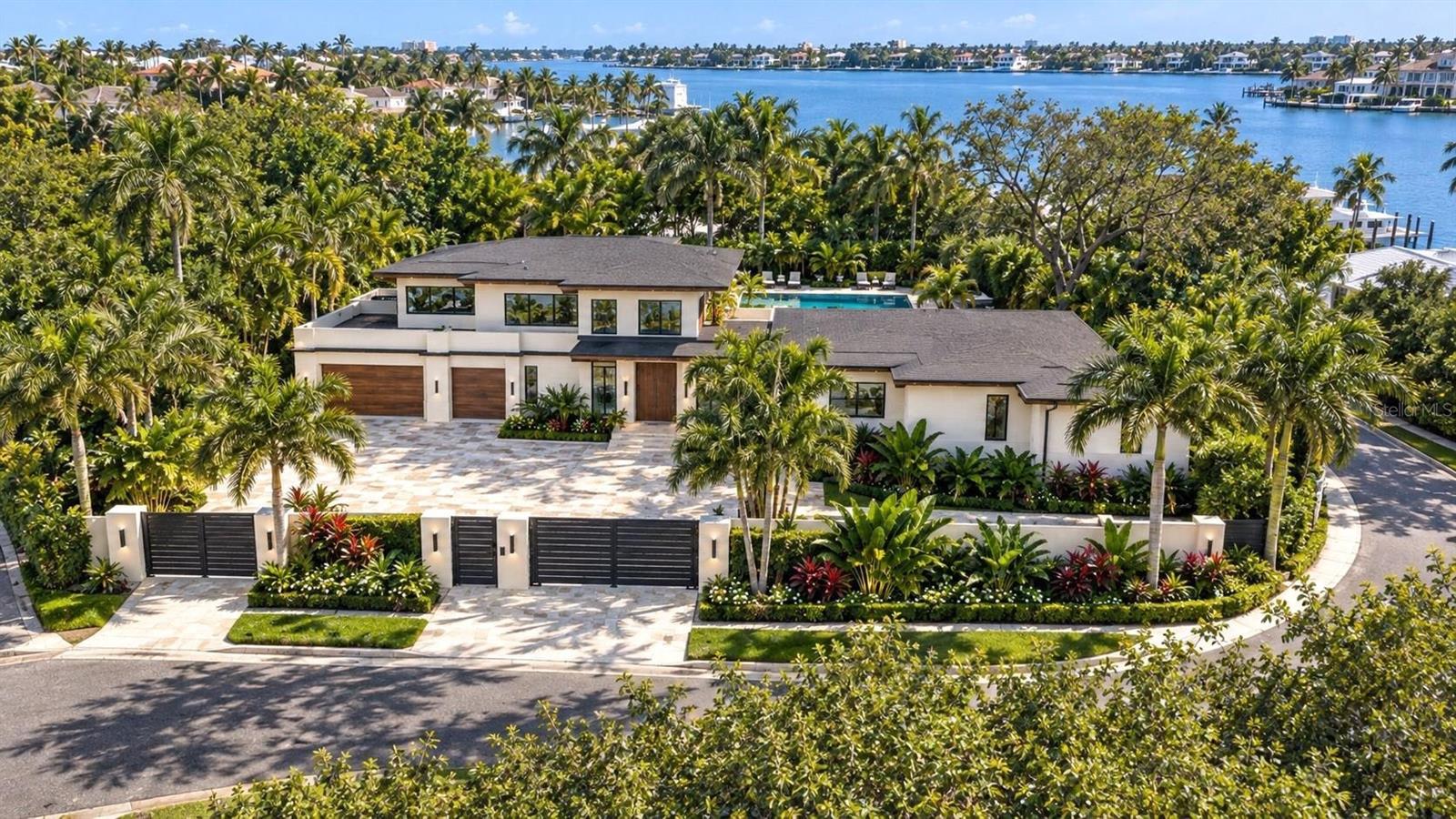 Pre-Construction. To be built. Completion anticipated in a few months. Situated West of the Trail, this exceptional estate represents the pinnacle of luxury living in Sarasota. Designed & built by Pham Development, this residence is a masterpiece of innovative, forward-thinking design and flawless craftsmanship. This home spans 7,445 square feet under roof, including 4,765 square feet of living space, with 5 bedrooms, 6 full baths, and 1 half bath. Inside, you'll discover an open floor plan that harmoniously blends expansive spaces with comfortable, luxurious living.

Soaring, 18-foot ceilings and seamless transitions to multiple patios and wrap-around balconies create an ideal setting for everyday living and entertaining, while a glass elevator adds convenience and architectural elegance. The kitchen showcases a quartz waterfall island, elegant pendant lighting, sleek custom cabinetry, and a premium appliance package featuring a 72-inch Sub-Zero refrigerator, Cove dishwasher, and Wolf range, coffee maker, and microwave. A spacious butler’s pantry provides additional storage, a secondary sink, and a dedicated prep area, while a glass-enclosed, temperature-controlled wine room beautifully displays your collection. Both the office and primary suite feature pillarless corner sliders, creating an uninterrupted indoor-outdoor transition. The expansive primary suite also offers 14-foot ceilings, abundant natural light, and a spa-inspired bathroom with a freestanding soaking tub, dual quartz vanities, and a frameless glass shower with multiple shower heads. A private theater room completes the interior, offering tiered seating, oversized leather recliners, and a wall-spanning ultra-high-definition projection screen.

Outside, the resort-style pool is the centerpiece of the backyard, complete with a built-in spa, waterfall, and ambient lighting. A natural stone deck, covered lanai dining area, and a fully equipped luxury outdoor kitchen and bar provide the perfect setting for outdoor living. A cozy fire pit with seating offers a perfect gathering spot for evenings, while the lush landscaping—featuring vibrant flower beds, mature trees, and decorative water features—creates a tranquil and picturesque setting. This outdoor space seamlessly combines comfort, style, and functionality for an exceptional living experience. Positioned on a grand parcel of approximately 20,505 square feet, this home offers privacy and tranquility amidst beautifully landscaped grounds. Whether you’re seeking the excitement of downtown Sarasota or the natural beauty of the Gulf, experience the perfect blend of luxury, comfort, and convenience in this exceptional home in a fabulous location. Includes virtual staging.