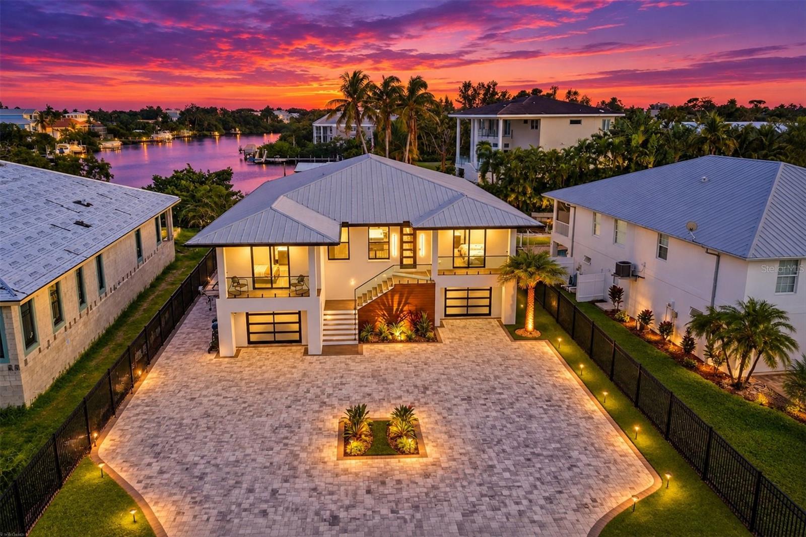 A boater’s paradise and an entertainer’s dream, this exceptional waterfront residence captures the very best of the Siesta Key lifestyle. Set along 83 feet of waterfront with direct access to Sarasota Bay and just a short walk to Beach Access 1 on Shell Road, the expansive home was thoughtfully designed for luxurious indoor-outdoor living and sophisticated entertaining. Featuring a grand entrance with an automated front gate, expansive stone-paver driveway, and abundant parking for entertaining, this waterfront property makes an undeniable statement.

Inside, glistening water views greet you at the door. Soaring 11-foot ceilings, 8-foot solid-core doors, impact-rated windows, and wide-plank luxury LVP flooring create a refined yet inviting atmosphere. At the heart of the home, the open-concept great room flows seamlessly through oversized sliding glass doors to the expansive 50-foot lanai. The chef’s kitchen features custom wood cabinetry, quartz countertops, premium Thermador and Bosch appliances, and an entertaining bar complete with a wine cooler, two beverage refrigerators, and an ice maker.

The primary suite provides a private retreat with his-and-hers walk-in closets and a spa-inspired bath featuring dual rain showerheads, a steam shower, soaking tub, and elevated stone finishes. Three additional bedrooms offer exceptional accommodations, including ensuite bathrooms with beautifully appointed finishes.

Outside, a heated pool with sun shelf, luxurious spa, and custom, in-ground fire pit create the perfect, private waterfront oasis. The newly installed dock, 10,000lb boat lift, and two jet ski lifts make getting out on the water effortless, with Sarasota Bay just minutes away. A private putting green, integrated indoor-outdoor speaker system, beautifully landscaped grounds, and whole-property fencing complete the resort-like setting. The lower level offers more than 2,500 square feet of ADDITIONAL space for vehicles, water toys, equipment, a home gym, game room, workshop, etc.

Overlooking Bayou Nettie, this premier waterfront setting places Sarasota Bay just moments away by boat. This is a home designed around the pleasures of waterfront living, uninterrupted entertainment and everyday enjoyment.