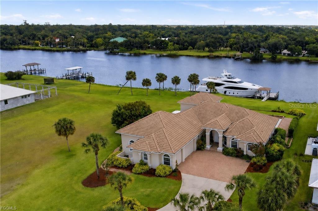 Caloosa Shores-one of LaBelle's most exclusive gated riverfront communities-this exceptional 3,355 sq ft home offers luxury style living and sits on a private 1 acre homesite along the Caloosahatchee River. Beyond its ideal location, this property has an almost endless number of upgrades and features both inside and out. From the moment you enter, the pool and expansive river views take center stage creating a stunning focal point that carries throughout the home. This custom-built residence showcases travertine flooring and high-end finishes blending quality craftsmanship with timeless design. The kitchen is thoughtfully designed to capture waterfront views featuring custom cabinetry, stainless steel appliances and a Wolf gas cooktop. The primary suite is a true retreat, offering serene river vistas and a spacious ensuite bath complete with travertine finishes, dual vanities, separate jetted tub and walk-in shower. Upstairs the bonus room opens to a balcony elevated approximately 35 feet above the river providing a unique vantage point, one of the best views on the river! This level also includes access to an oversized walk-in attic offering convenient storage and ease of maintenance. The approximate 1900 sq ft garage will accommodate multiple vehicles and the 12' X 16' garage door and 50 amp outlet provides storage for your RV. Situated at approximately 24 feet of elevation, flood insurance is not required. Closed cell spray insulation throughout the home provides safety and energy efficiency. The outdoor living experience is equally impressive. Additional features include PGT impact windows and sliding glass doors, whole house reverse osmosis water system, 20 kw Generac generator, 500 gal propane tank, 2 Rinnai tankless water heaters, full irrigation system with river pump or well pump and a comprehensive security system. The spacious patio and pool overlook the river creating an ideal setting for both relaxation and entertaining. For boating enthusiasts, the property boasts an approximate 900 sq ft private dock with composite decking, 10,000 lb lift and tile roof. Combining an exceptional location, breathtaking views and a wealth of high-end upgrades this one of a kind riverfront home delivers the ultimate Southwest Florida lifestyle