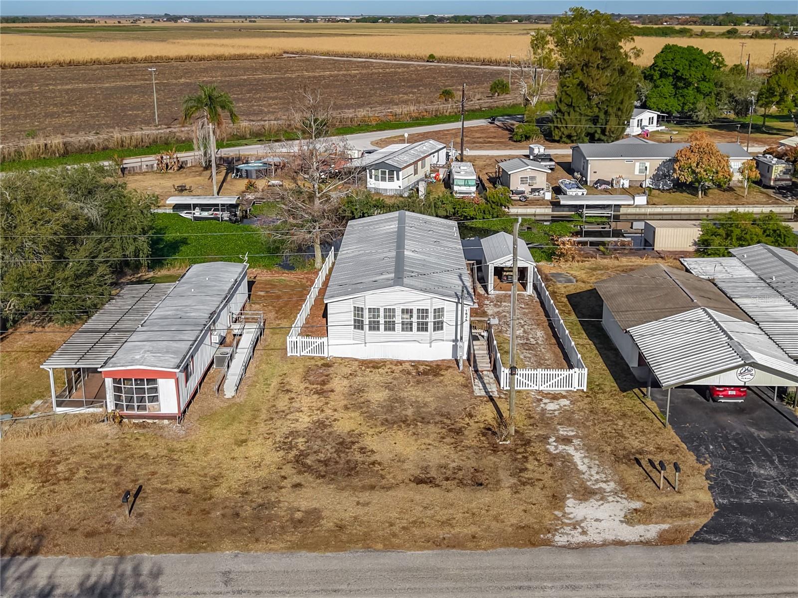 If you're looking for a waterfront, worry-free home, this is it! This home has NO HOA, and NO LOT RENT!  Built in 2023, this nearly new home is ready for its new owner! Not only do you have a canal behind the home, you have the Caloosahatchee Canal in front of the home, and you are able to even able to build a dock on the canal, with approval from the Water Management District! The current sellers are the ones who put the home on the lot, and they did additional upgrades to the home, most notably adding the sun room in the front, perfect for watching the sunset, and the boats going past! The living space is open, with the sun room, living room, dining area, and kitchen all flowing together. The bar height kitchen island divides the room, while keeping it flowing, and there is no shortage of cabinet space in the kitchen! The guest bedroom is a great size, and has a walk-in closet. The guest bathroom features a shower / tub combo. The master suite encompasses the entire rear of the home, with an additional sitting space, walk-in closet, and ensuite bathroom with walk-in shower. The washer and dryer are inside, in the mud room, and outside you'll find a storage shed, plus a white picket fence around the home. With the home being just a few years old, there is no immediate need to make major replacements (such as roof, appliances, and HVAC). And even though the home is encompassed by water, FLOOD INSURANCE IS NOT REQUIRED. The home is being sold furnished. Schedule your showing today!