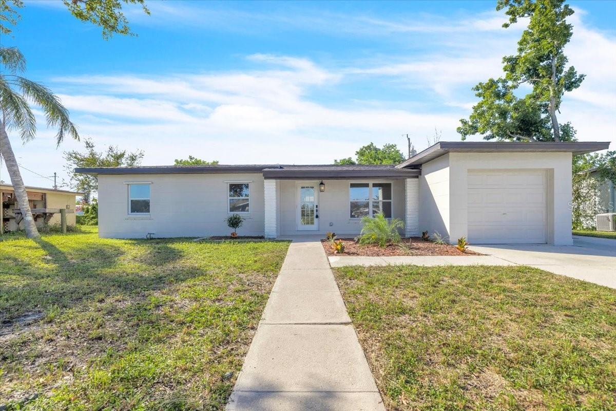 OPEN HOUSE THIS SATURDAY 10/31 from 12-2pm ||  Ask anyone shopping for a home in Florida right now what they check first, and it isn’t the kitchen. It’s the roof. Here, it went on in 2026, and the AC, windows, and doors are all new too, with hurricane shutters on top of that. Then the inside got the same treatment: a brand-new kitchen, a brand-new bathroom, new floors, and fresh paint everywhere. Nobody has lived here since, so you’d be the first to scuff anything.

Fresh landscaping leads up to a covered front porch with exposed wood beams, made for two chairs and waving at whoever walks by. Inside, the living and dining area runs straight back to three sets of sliding glass doors, which is a lot of glass for one wall and exactly the right amount.

The kitchen has white shaker cabinets, butcher block counters, subway tile, stainless appliances, and a skylight that keeps it bright enough you’ll stop reaching for the light switch. The door to the garage is right there too, so groceries go from the car to the counter in about four steps. Three bedrooms share one fully redone bathroom with a walk-in tiled shower.

Those sliders open to a 22-foot screened porch, which is where your mornings and most of your evenings will end up. Past that is a paver patio and a big backyard with mature trees doing the shade work for free. Add an attached garage, no HOA, and public water and sewer, which in Port Charlotte is not a given.

Sharon Circle Park is right down the street, and you’re a couple of blocks off US 41, so Publix and a lineup of local seafood, BBQ, and Cuban spots are minutes away. Head down 41 and you’re at the Charlotte Harbor waterfront and Sunseeker Resort in no time. The only real decision left here is where the couch goes.