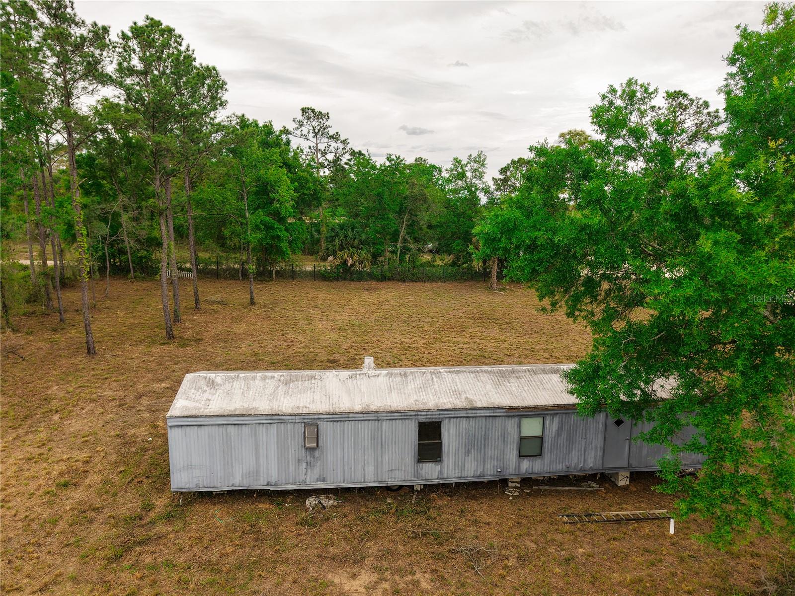CASH ONLY. Welcome to your slice of country paradise in beautiful Williston, Florida! Nestled on a serene and private 1-acre corner lot zoned Agricultural, this property is perfect for those seeking space, flexibility, and a relaxed rural lifestyle. Property features a new well and septic. This lot is fully fenced and cleared. Whether you're searching for a peaceful primary residence, a weekend retreat, or a smart investment opportunity, this property offers incredible potential with room to grow.  Newer manufactured homes on 1-acre lots in the area are selling between $252,000 and $300,000, making this an excellent opportunity with strong upside potential.  Enjoy peaceful outdoor living with NO HOA, surrounded by nature, with ample space to create your dream garden, add outbuildings, or start your own hobby farm. With flexible Agricultural zoning, you can bring your chickens, goats, etc. Conveniently located just minutes from downtown Williston.  Outdoor enthusiasts will love the proximity to nearby springs, state parks, and scenic equestrian trails, making this an ideal setting for those who enjoy Florida’s natural beauty. The mobile home on the property is a fixer-upper and will require repairs and updates to bring it to a livable condition, making this an excellent opportunity for investors, renovators, or buyers looking to customize a home to their liking.