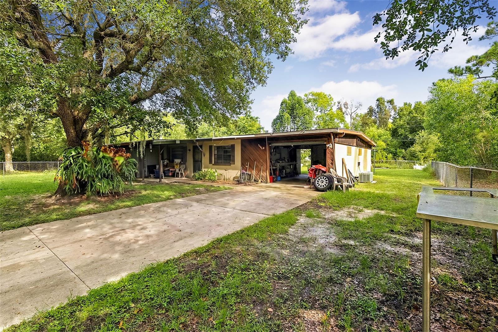 This 2-bedroom, 1-bathroom home in Punta Gorda offers a unique opportunity for buyers looking for an affordable property with plenty of potential. The home features a functional layout with a spacious living room, dining area, kitchen, dedicated office/flex space, laundry room, and a large screened porch ideal for relaxing or entertaining. The property sits on a generous, tree-lined lot with a fenced yard, mature landscaping, covered outdoor areas, and additional space for storage or equipment. Inside, the home retains plenty of character with brick-style flooring, stone accents, wood paneling, and a traditional layout, while the existing condition provides an opportunity for a buyer to update and personalize the space to their taste. With its outdoor living areas, flexible floor plan, and desirable Punta Gorda location, this property could be a great option for a primary residence, seasonal home, or investment project.