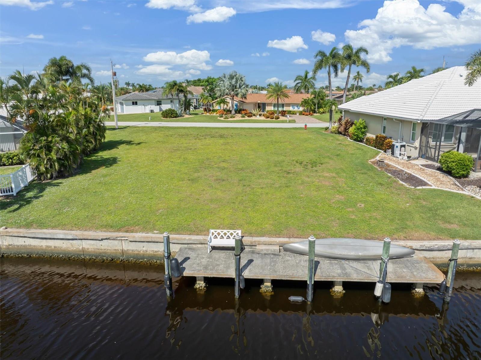 WATERFRONT HOMESITE IN PUNTA GORDA ISLES. Build the luxury home you’ve been dreaming of on this exceptional waterfront lot in desirable Punta Gorda Isles! Imagine starting your day with peaceful water views from your future lanai and ending it with an evening cruise from your own dock. This property offers a fantastic boating lifestyle, with quick access to open water in approximately 10 minutes by boat and the option to stop along the way at popular Fishermen’s Village for waterfront dining, shopping, entertainment and concerts at the renowned Military Heritage Museum.
The 9,868 sq ft lot features a 30-foot concrete dock, refreshed with new pilings in 2021, and is ready for your powerboat or future lift. The concrete seawall is maintained by the city for added peace of mind. Public water and sewer are available, making this a prime setting for the luxury residence you’ve been dreaming of.
Ideally located just a short bike ride or drive from charming historic downtown Punta Gorda, you’ll enjoy easy access to fabulous restaurants, boutiques and local art. Punta Gorda Airport is nearby, with Allegiant providing nonstop service to numerous destinations, making travel simple and convenient. Gulf beaches in Englewood, Sarasota, and Fort Myers are also within reach for even more opportunities to enjoy Florida’s coastal lifestyle.
Enrich your life in this wonderful small town community. Away from the hustle, but close enough to explore new adventures.
Whether your ideal day includes boating, fishing, kayaking, biking or simply relaxing by the water, this is an rare opportunity to create an extraordinary Florida retreat. Don’t wait. Call today!