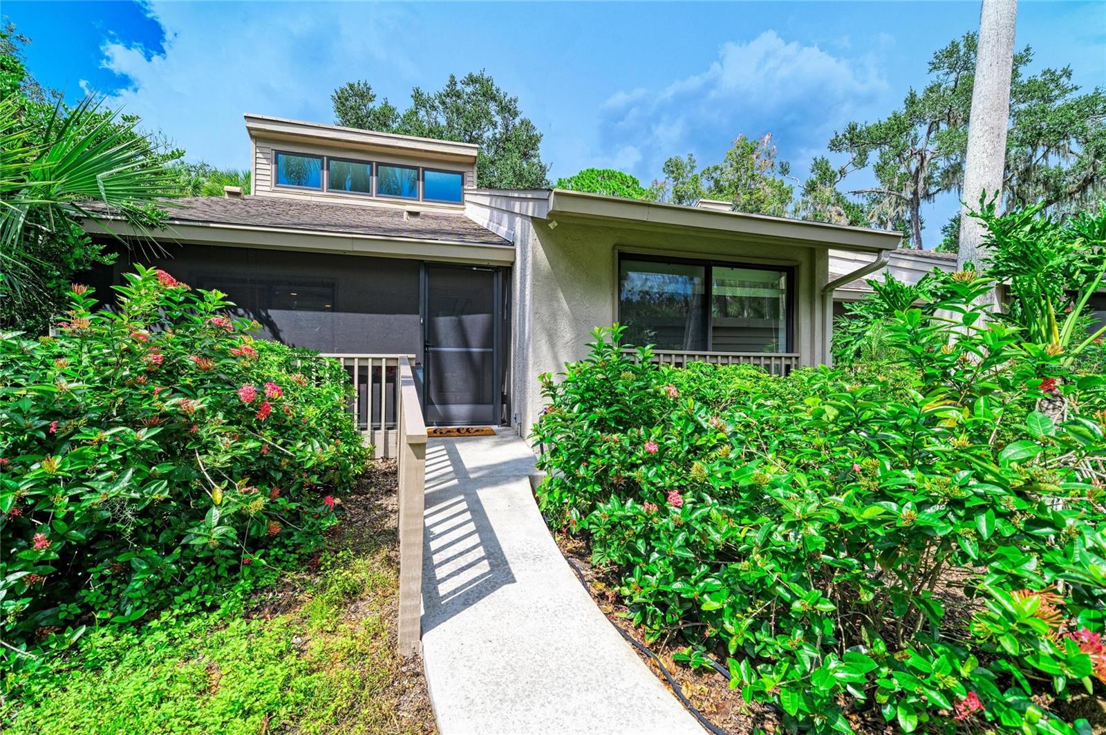 Imagine escaping into nature every single day without ever leaving Sarasota! Welcome to Arboreal, where city convenience meets the serenity of a secluded tropical retreat. Villas are discreetly tucked in among the greenery alongside the winding, tree-canopied roads. Nestled within this community is a beautifully remodeled end-unit villa with soaring vaulted ceilings, a custom loft, and exceptional privacy, with no neighboring villas visible from the front, side, or rear.

One of the home's most captivating features is its exceptional indoor-outdoor living! Multiple sliding glass doors connect three distinct outdoor spaces. Enjoy your morning coffee on the spacious screened front porch, accessible from the entrance and kitchen; relax on the covered, screened side lanai with skylights and oversized screens, accessible from the living and dining rooms; or step onto the open-air rear deck from the living room or primary suite. Surrounded by a spectacular canopy of mature trees and tropical foliage, these peaceful spaces invite you to watch wildlife, listen to the soothing sounds of rain frogs, and unwind in complete tranquility. Whether entertaining friends, sharing an evening outdoors, or enjoying a quiet afternoon with a good book, there's a perfect spot for every occasion.

Inside, the home is equally impressive! Professionally remodeled in 2018 with high-end finishes and exceptional attention to detail, this home features a bright, spacious open floor plan and engineered wood flooring throughout. The kitchen boasts white oak cabinetry with custom pull-out drawers and organizers, quartz countertops, stainless steel appliances, and ample storage. A unique custom backsplash features an actual photograph of the wooded view from the rear deck, taken shortly before the 2018 renovation. This unexpected design detail beautifully brings the outdoors in! A pantry and concealed washer and dryer complete this thoughtfully designed space, while the open living and dining areas are ideal for entertaining.

The expansive custom-designed loft overlooks the living room, offering endless possibilities for a home office, guest retreat, creative studio, or private lounge. Beautiful built-in shelving adds character and functionality, while an adjoining room, currently used for storage, offers additional possibilities as a cozy reading nook, hobby room, or potential future bathroom. The staircase was also designed to accommodate a future chair lift.

The generous primary suite features vaulted ceilings, sliders to the rear deck, and custom closet built-ins. Both remodeled bathrooms offer tiled showers with sleek linear drains; the primary bath also has custom mirrors and an oversized storage closet. A welcoming guest bedroom completes the layout. Thoughtful finishes and exceptional storage can be found throughout the home.

Additional improvements include complete replumbing and HVAC replacement in 2018. A covered carport and separate storage unit add convenience. Arboreal also offers a large screened swimming pool within the community grounds.

With extensive renovations, distinctive architecture, a versatile loft, remarkable privacy, and exceptional indoor-outdoor living, this is far from ordinary condo living! This one-of-a-kind residence combines high-end finishes and an extraordinary natural setting to create a home as unique as its surroundings. Come experience the beauty, serenity, and charm of Arboreal for yourself!