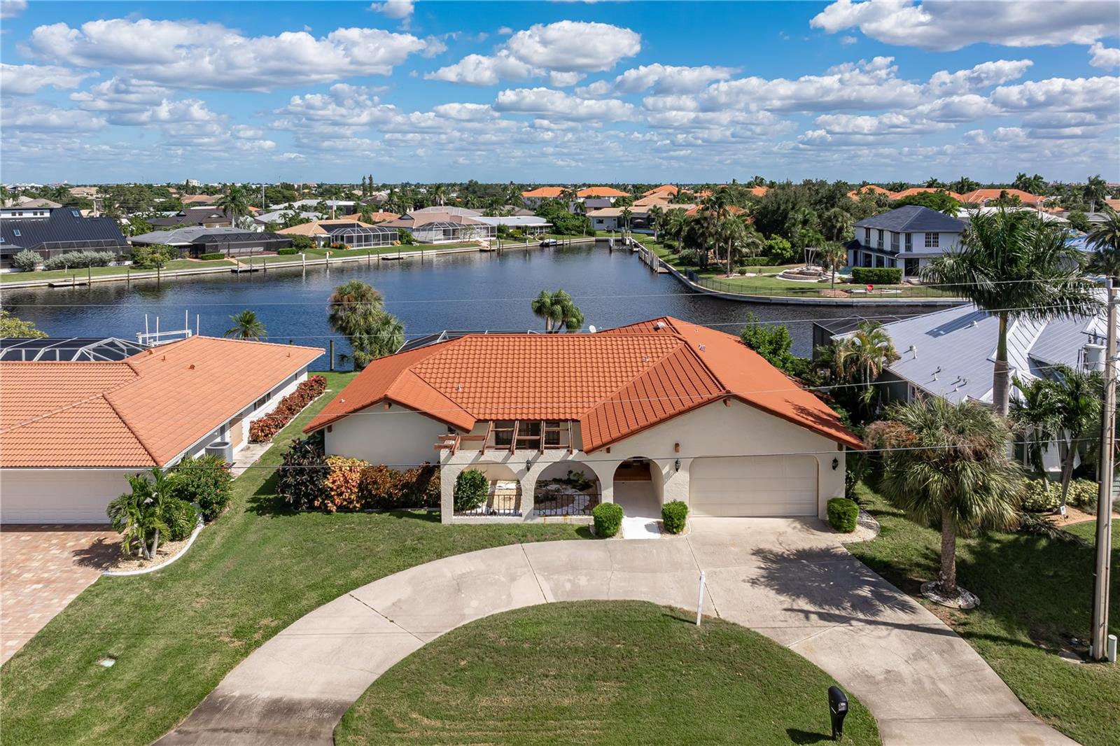 WHAT A VIEW! PGI WATERFRONT HOME W/SPECTACULAR CANAL BASIN VIEW & QUICK, DEEP SAIL ACCESS! NEW ROOF in 2024. Check out this 3 bed/2 bath waterfront pool home in Punta Gorda Isles w/2,013 sqft of living space, a 30ft concrete dock & quick access to open water. Reach Charlotte Harbor in mere minutes from your backyard! SO MUCH POTENTIAL HERE! This home offers a fantastic opportunity to create your ideal Florida waterfront getaway while enjoying a location that's hard to beat. Inside, the spacious floor plan features an L-shaped formal living room & dining room plus a separate family room w/built-in wet bar. The centrally located kitchen connects the formal living/dining area to the family room & adjacent breakfast nook, creating a functional layout w/plenty of room for entertaining. Kitchen offers solid surface counters & a pass-through window to the lanai - perfect for serving drinks & snacks poolside. The home's layout provides multiple gathering spaces while offering endless possibilities to update & personalize to your taste. The home boasts three bedrooms including a master suite w/private bath & walk-out access to the lanai, allowing you to step outside & enjoy the pool and waterfront setting whenever you please. Both guest rooms enjoy canal views, giving your visitors a front-row seat to the beautiful waterfront setting. One guest bedroom also features sliding glass doors w/walk-out access to the pool & lanai. The guest bedrooms share a hall bath that doubles as a pool bath w/direct access to the lanai - ideal for cleaning up after a day spent on the water or lounging poolside. Outside is where this property truly shines! The large lanai surrounds an in-ground pool & overlooks a SPECTACULAR, WIDE CANAL BASIN VIEW. Picture relaxing poolside w/your morning coffee, watching boats pass by or enjoying an evening cocktail as the day winds down. There's plenty of room to entertain friends & family while taking full advantage of Florida's year-round sunshine. A brick patio offers another spot to sit back & enjoy the outdoors. Boaters will appreciate the wide basin that provides ample room for turning & maneuvering when heading out or returning to the dock. Just steps from the back door, you'll find a 30ft concrete dock. Keep your boat docked in your backyard, ready to set off on your latest adventure at a moment's notice. Reach open water in minutes & start enjoying some of the best fishing & boating SW Florida has to offer! Other amenities include an attached two-car garage w/an 8x11 workshop - perfect for the tinkerer, hobbyist or anyone needing extra space for projects & storage. A circular driveway adds convenience & additional parking. Punta Gorda Isles is known for its active waterfront lifestyle w/miles of sidewalks connecting you to area parks, Fishermen's Village, Isles Yacht Club & historic downtown Punta Gorda. Enjoy nearby shopping, dining, golf & waterfront activities. COME FOR THE VIEW & MAKE THIS HOME YOUR OWN! Don't miss this opportunity to own a piece of paradise in PGI. Make an appointment today!