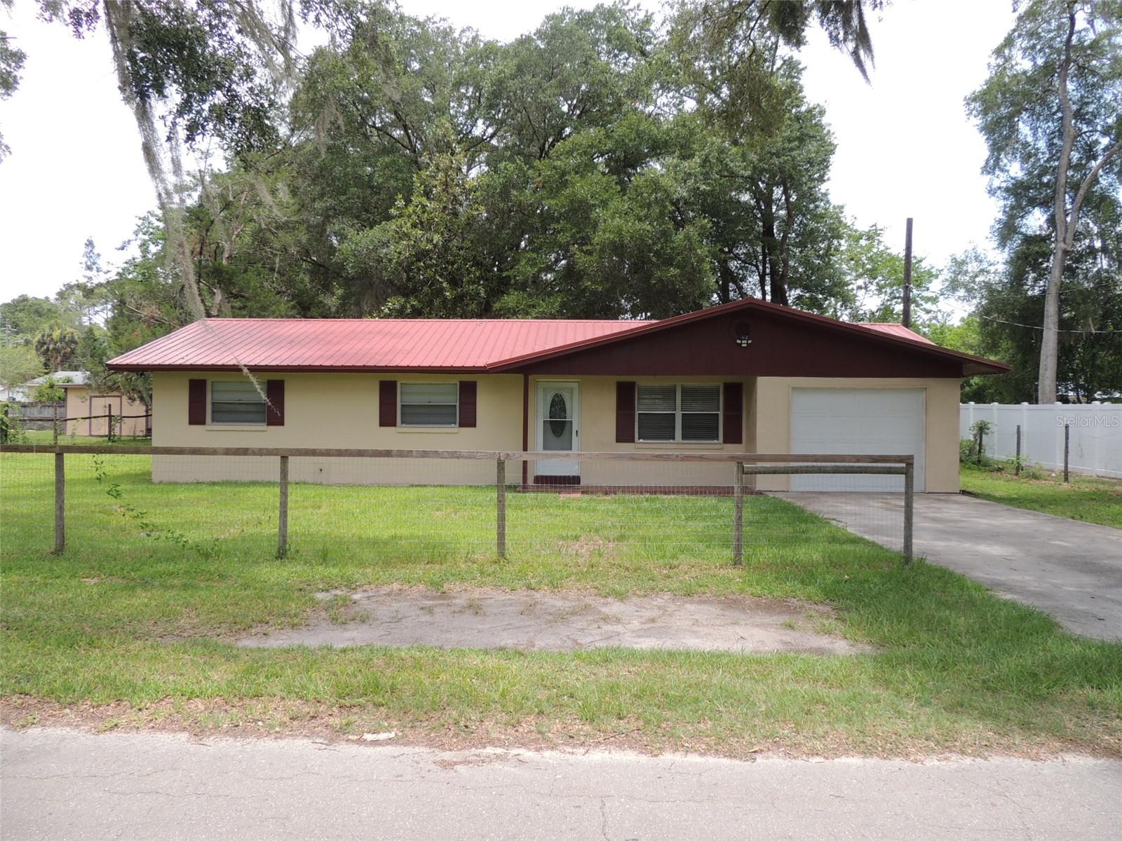 Auction Property. MOVE-IN READY CONCRETE BLOCK/STUCCO HOUSE IN TOWN!! This 3 bedroom, 1-1/2 bath concrete block home has been updated with new kitchen cabinets, new appliances, pantry, updated bathrooms, ceramic tile floors, upgraded electric, newer metal roof and newer A/C. Attached garage and sits on two city lots with a large back yard. City utilities and a short walk to the Post Office, Grocery Stores, Churches and Drug Stores. Just a short, scenic drive from both Gainesville and Ocala, this property makes it convenient to experience a variety of shopping, dining, medical, and event options.