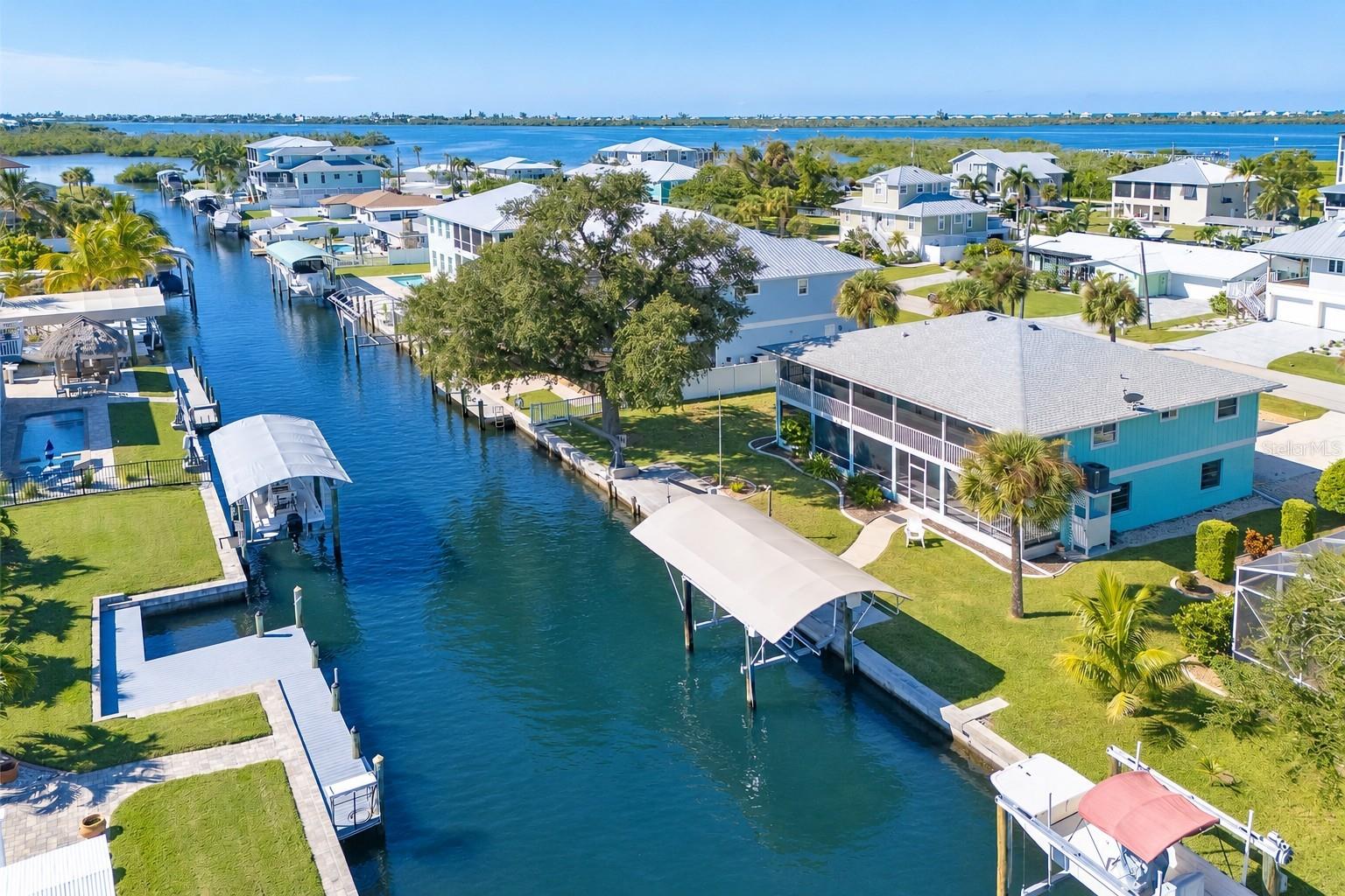 Virtually Staged. Experience exceptional Florida waterfront living in this ELEVATED 3-bedroom, 2-bath coastal retreat with a 4-CAR GARAGE, workshop, and 1,778 square feet of garage and storage space. Enjoy BOATABLE DEEP-WATER ACCESS with a short ride to the Intracoastal Waterway and Gulf.NO HOA.  Perfectly positioned on an oversized lot, the property boasts 100 FEET OF CONCRETE SEAWALL, a CEMENT DOCK WITH POWER, and a COVERED BOAT LIFT, creating an outstanding setup for serious boaters. With sailboat-accessible water and no fixed bridges to limit your boating lifestyle, this is a rare opportunity to enjoy effortless access to some of Southwest Florida’s most desirable waterways.
Multiple outdoor living spaces elevate the coastal experience, with screened lanais on both levels capturing peaceful water views and a wraparound porch perfectly positioned to enjoy both sunrise and sunset. An extended waterfront entertaining area provides even more space to relax, gather with friends, and take in the views just steps from your dock.
A truly exceptional feature is the entire 1,774-square-foot lower-level garage and storage area, offering an extraordinary amount of flexible space rarely found in a waterfront property. BRAND NEW durable epoxy/polyaspartic floor coating with TRANSFERRABLE Warranty, fresh paint, and NEW LIGHTING, this expansive area also includes built-in shelving and a workbench. There is abundant room for a golf cart, boating and fishing gear, kayaks, bicycles, workshop space, recreational equipment, and extensive storage. The improvements continue into the lower-level lanai, creating a clean, bright, finished space that adds even more versatility for entertaining, hobbies, and waterfront living.
The elevated main living level is designed to embrace the views, with large sliding glass doors filling the spacious great room and dining area with natural light while creating a seamless connection to the waterfront lanai. The updated kitchen features granite countertops, beautiful cabinetry, three pantries, a built-in desk, and direct lanai access, making it equally suited for everyday living and entertaining.
The primary suite offers a private retreat with dual built-in closets and an ensuite bath featuring granite countertops and a walk-in shower. Two additional guest bedrooms provide excellent flexibility, including one with a Murphy bed and direct lanai access that works beautifully as a home office or guest suite, along with an oversized secondary guest room and well-appointed guest bath. All three bedrooms have been refreshed with NEW CARPET, enhancing the home's clean, move-in-ready appeal.
Additional updates include a 2023 roof, 2023 A/C, 2024 water heater, and 2024 refrigerator and microwave, along with elevated HVAC placement for added peace of mind. The elevated design provides an important advantage for waterfront living, with NO FLOODING TO THE MAIN LIVING LEVEL during past storms or storm surge events. Beautiful landscaping further enhances the property's coastal setting.
With deep-water boating access, approximately 100 feet of seawall, private dock and boat lift, expansive garage and storage space, multiple waterfront living areas, and an elevated main living level, this property delivers the lifestyle waterfront buyers are searching for. Move-in ready and designed around the water, it is a rare opportunity to enjoy boating, breathtaking views, and effortless access to the Intracoastal Waterway and Gulf—all from your own backyard.