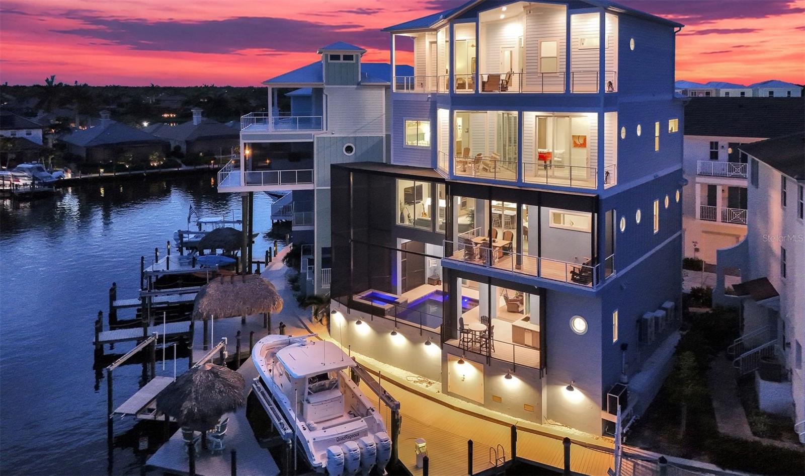 A PRIVATE WATERFRONT RESORT IN THE HEART OF CAPE HARBOUR. This luxury residence is more than a home, it is an experience. Set on a rare double lot with direct boating access and sweeping views over the mangrove preserve, this 4 story coastal estate was designed for those who want the very best of Cape Coral waterfront living. With a private elevator servicing all 4 floors, 4 furnished decks, balcony access from every bedroom, a screened heated saltwater pool and spa, full outdoor kitchen, waterfront bar, tiki hut, private dock, and two boat lifts (30k & 15k), every detail supports a lifestyle centered around boating, entertaining, relaxation, and unforgettable views. Inside, the home delivers refined coastal elegance with soaring ceilings, tile flooring throughout, tray ceilings with lighting, walls of glass, and expansive indoor outdoor spaces that frame the water from every angle. The gourmet kitchen is the centerpiece of the main living level, featuring a large island with seating, dual tone cabinetry, cabinet lighting, KitchenAid appliances, cooktop with vented hood, double wall oven, oversized refrigerator, pot filler, designer backsplash, wine cooler, pendant lighting, and a wet bar area with built in espresso and cappuccino maker. The open concept living and dining areas are ideal for gathering, with an 8 person dining table, additional seating, and a seamless connection to the oversized balcony overlooking the water. Designed with comfort and privacy in mind, the residence offers spacious bedroom suites, en suite bathrooms, generous closet space, and kitchenettes on multiple levels. The second floor includes 2 bedrooms, a kitchenette, walk in closet space, and beautifully finished bathrooms with both tub and shower options. The 4th floor honeymoon suite feels like its own private escape, complete with a private deck, kitchenette, coffee bar, sink, washer and dryer, quartz countertops, tall ceilings, custom closet cabinetry, dual vanity, soaking tub, and oversized walk in shower. A game room with foosball and additional sleeping accommodations adds flexibility for guests, extended family, or luxury rental use. The outdoor areas are truly unforgettable. Enjoy sunrise coffee from one deck, sunset cocktails from another, then spend the day boating, kayaking, grilling, relaxing by the pool, or soaking in the spa as the water and mangroves create the perfect backdrop. The pool level includes a full bathroom, making it easy to rinse off after boating or swimming, while the full outdoor kitchen with ice maker, gas grill, and waterfront bar creates the ultimate entertaining space. With multiple A/C units, raised pool and A/C equipment, 2 washer and dryer sets, high speed internet, abundant storage, driveway parking, additional on site parking, and the rare combination of luxury finishes, private elevator access, and direct boating from Cape Harbour, this property stands in a class of its own.