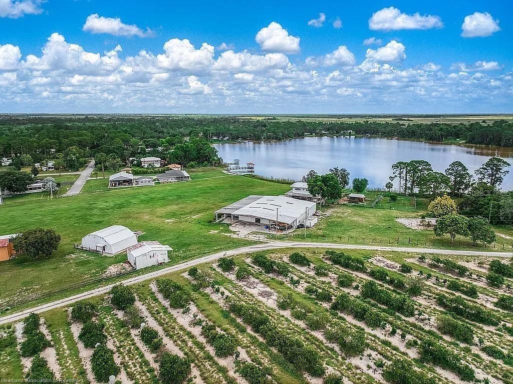Experience the ultimate live-work-play lifestyle at this rare Highlands County retreat featuring a updated 2-story, 2,400 SF lakefront home with wraparound porches, paired with over 10,000 SF of insulated steel hangars and workshops alongside a private 2,000’ grass airstrip. Why settle for a basic barndominium when you can own a true aviation and mechanics paradise with unmatched versatility, income potential, and lifestyle value? Situated on just under 1.65 private acres on a quiet dead-end street surrounded by orange groves, this one-of-a-kind property offers lakefront living, fly-in access, massive workspace, and room for all your toys, hobbies, and business needs—all just 15 minutes from Sebring, Sebring International Raceway, and the Sebring Airport. The home features 2 bedrooms, 2 baths, breathtaking sunrise and sunset views, and expansive country-style wraparound porches overlooking the lake and runway. A private concrete boat ramp makes it easy to launch your boat, tinker with projects, or enjoy the waterfront lifestyle. The insulated airplane hangars can accommodate multiple airplanes, RVs, boats, race cars, trucks, agricultural equipment, or virtually any large-scale hobby or business operation. Equipped with 220V electric, built-in air lines for tools, an air-conditioned workshop, and office space, the property is ideal for mechanics, aviation enthusiasts, fabricators, collectors, contractors, or entrepreneurs looking to combine business, storage, and recreation in one location. Additional improvements include a separate storage/workshop building perfect for a paint booth or additional garage space, plus a 20x15 poultry barn with six stalls and feed room for animals or hobby farming. Mature mango trees and peaceful rural surroundings complete the setting. A truly rare opportunity to own lakefront property with hangars, runway access, workshop space, and a comfortable country home—all in one. Enjoy lower costs, more freedom, and a higher quality of life while living, working, and playing from your own private compound. Properties like this rarely come available and do not last long—don’t miss this exceptional opportunity!