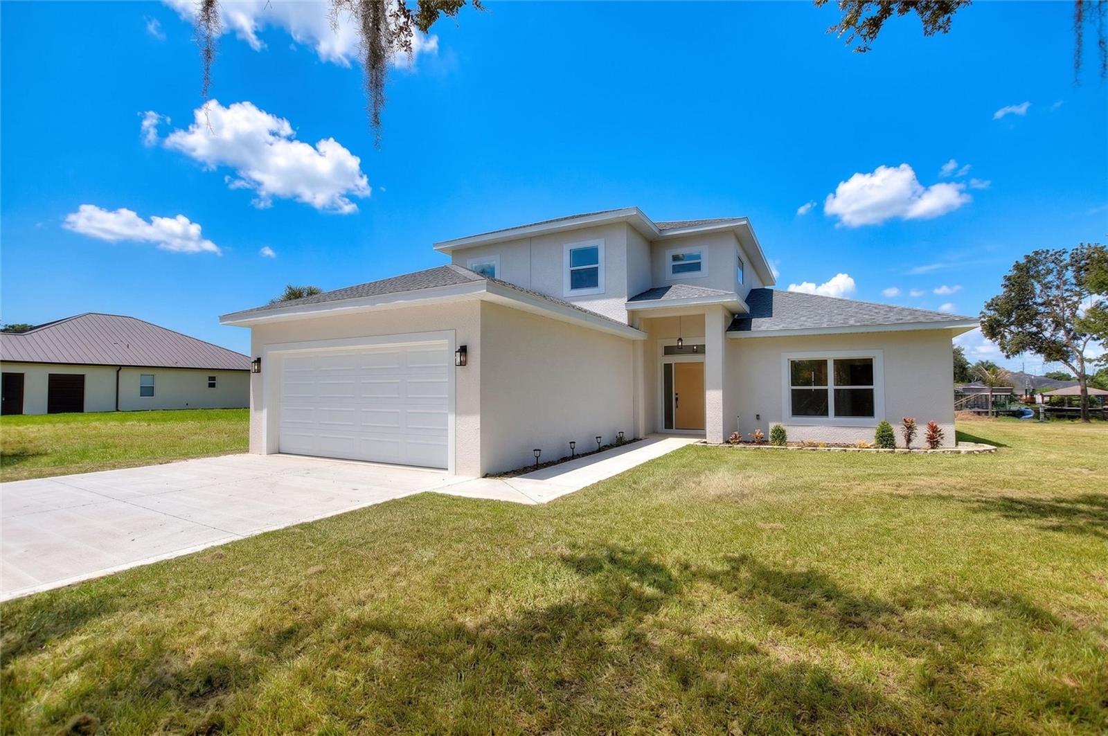 *PRICED $20K BELOW TOTAL BUILD COST AND UNDER APPRAISAL.* Welcome to your brand-new construction waterfront dream home in Lake Placid, Florida. This spectacular property perfectly blends modern farmhouse elegance with premier canal-front living to offer the ultimate Florida lifestyle. From the moment you arrive, the striking contemporary front elevation, pristine concrete driveway, and oversized two-car garage deliver a powerful first impression. The direct overhead drone perspective highlights the thoughtful footprint of the home, situated beautifully on an expansive cleared lot with an immaculate new roof.

Step through the custom front entry into a soaring, light-filled sanctuary designed for effortless open-concept living. The heart of the home features a dramatic two-story great room, beautifully framed by premium light oak-look flooring, crisp neutral tones, and high-set architectural windows that flood the entire space with natural light. Look up to admire the elegant second-story loft overlook. The seamless indoor flow connects the grand living area directly to your dining space and a gourmet chef’s kitchen. This sparkling kitchen is a masterpiece of form and function, boasting custom white shaker cabinetry with matte black hardware, a vast entertainment island topped with gleaming quartz, premium stainless steel appliances, and dual rustic-modern industrial cage pendant lights.

Pass through the massive sliding glass doors in the great room to experience true backyard paradise and direct water access. You can relax in the shade under your expansive covered lanai, complete with an outdoor ceiling fan, as you look down the peaceful waterway. The sweeping property lines show off a vast, open backyard with endless space for a custom pool, garden, or private dock. Bring your boat, jet skis, and fishing gear, because the incredible aerial overviews reveal an exceptional location on a wide, deep canal just moments away from the wide-open waters of the lake. Every square inch of this magnificent home exudes quality, cohesion, and style, making it the perfect waterfront retreat for its very first owners.