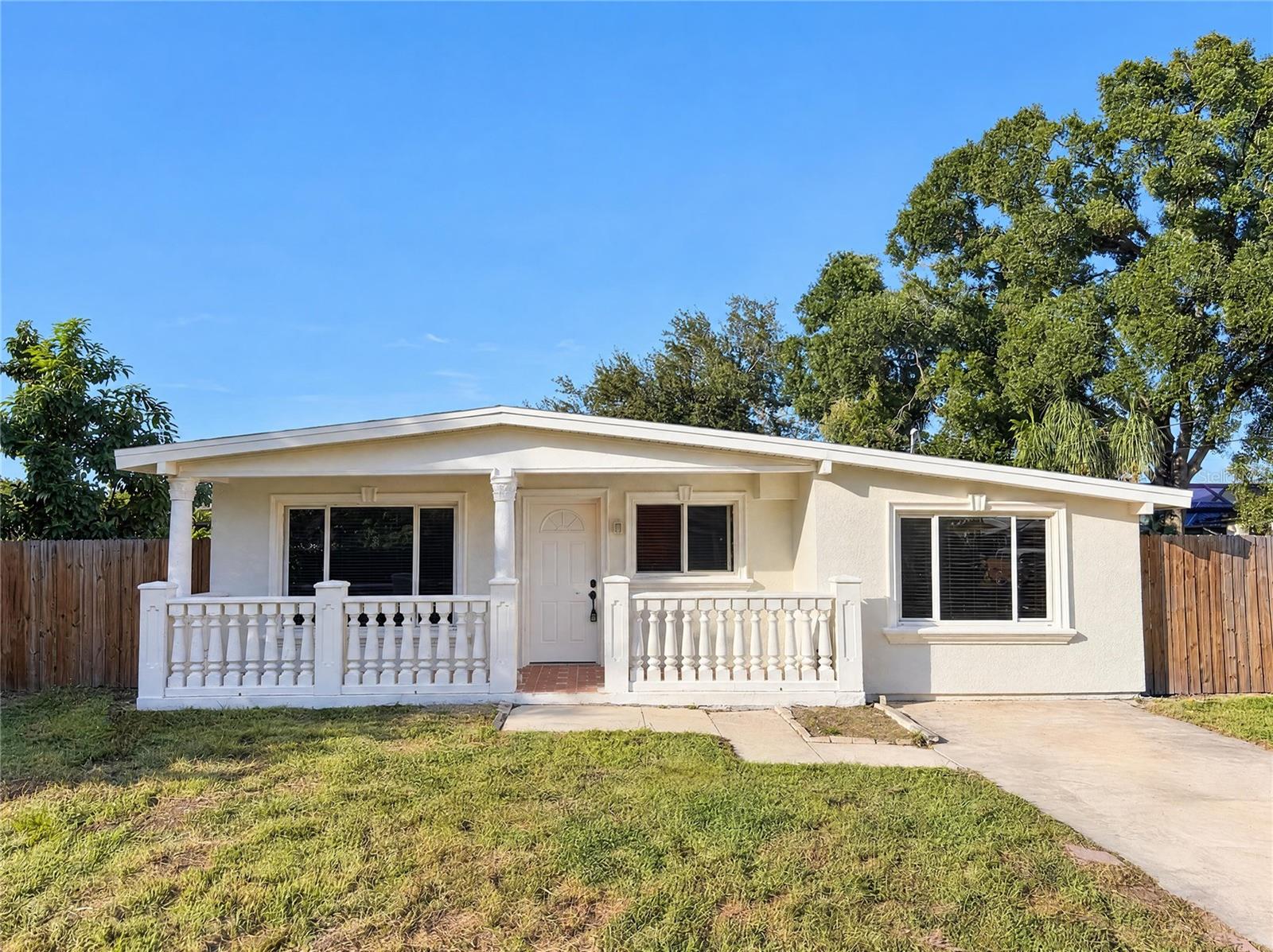 3205 W Rogers Ave is a one-story Tampa home with four bedrooms, two bathrooms and over 1,400 sq ft of living space. A covered front porch leads into the living room, which connects to the kitchen and its raised breakfast bar. A separate dining area sits beside the kitchen. Both bathrooms have walk-in showers. The rear patio opens to a yard with a detached storage shed, while a sheltered outdoor utility alcove provides laundry connections. An additional room off the hall adds space beyond the four bedrooms. Included 100-Day Home Warranty with buyer activation