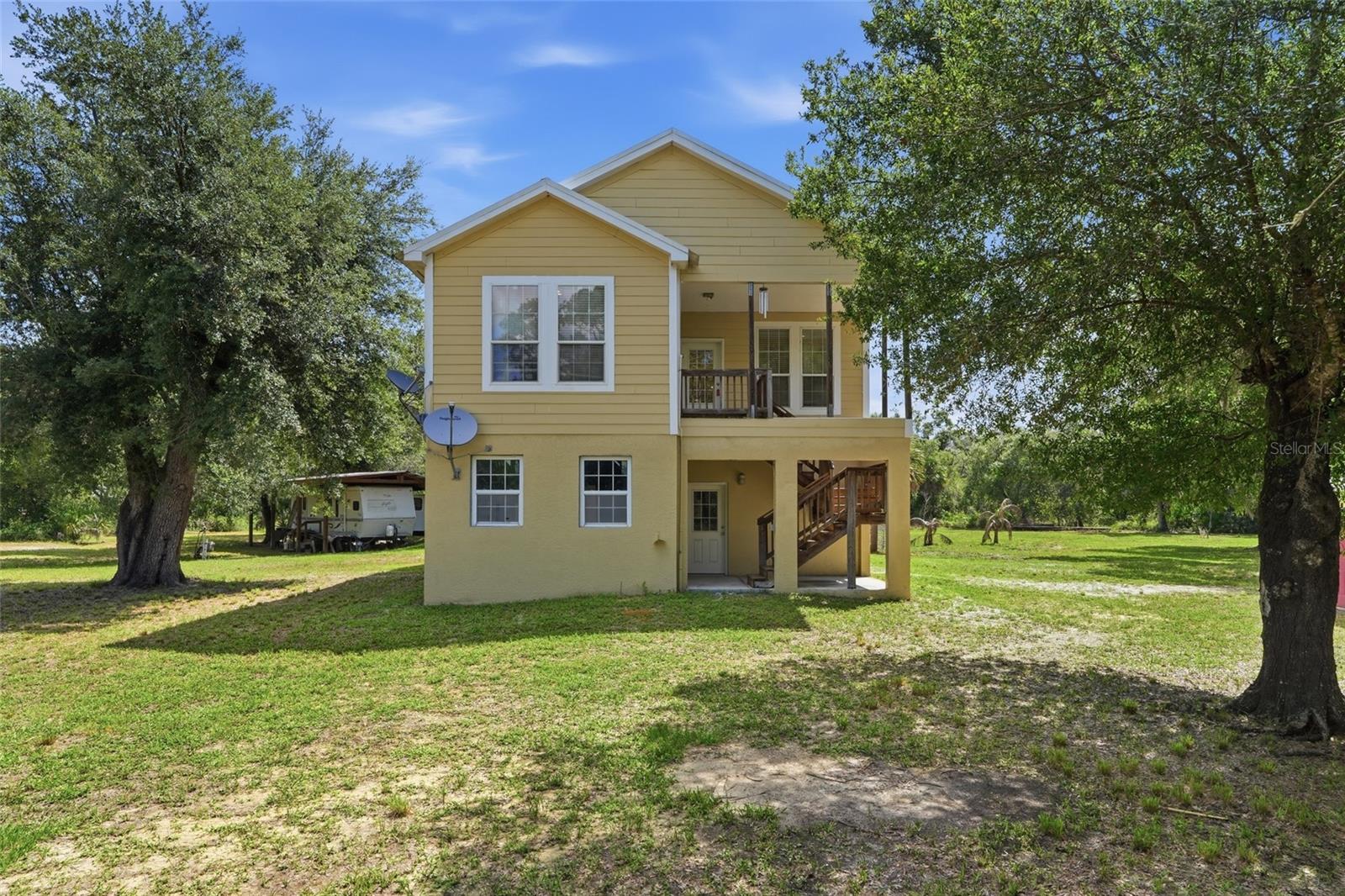 Tucked away at the end of a beautiful tree-lined driveway, this one-of-a-kind property offers the privacy, space, and charm you've been searching for. Situated on approximately 5 acres and zoned for animals, this property is ready for everything from hobby farming to simply enjoying a little extra elbow room and country living. The home occupies the entire second level and features a thoughtfully designed split-bedroom floor plan with three bedrooms and two bathrooms. Inside, you'll immediately notice the gorgeous wood floors, abundant natural light, and welcoming living room complete with built-in shelving and a fireplace that creates the perfect gathering space. Storage is plentiful throughout, including a spacious indoor laundry room and an oversized hallway closet. The kitchen is truly the heart of the home and a dream for anyone who loves to cook or entertain. Complete with granite countertops, a center island, breakfast bar, and an impressive amount of cabinetry, there's a place for everything. Just off the kitchen, you'll find a charming breakfast room with access to a private deck overlooking the property, making it the perfect spot for morning coffee or evening sunsets. The dining room is equally impressive with unique Florida-inspired wallpaper and beautiful natural lighting that makes every meal feel special. The oversized primary suite offers plenty of room to unwind, along with a massive walk-in closet and spacious en-suite bathroom. Downstairs, the entire first floor is dedicated to an incredible 5-car garage with endless storage possibilities for vehicles, equipment, toys, or workshop space. Outside, the opportunities are endless. With approximately 5 acres of land, a pole barn already in place, and zoning that allows animals, this property is perfectly suited for those dreaming of a mini farm, equestrian setup, or simply enjoying the peace and freedom that comes with country living. Properties offering this much space, storage, and versatility don't come along often. Come see what life could look like when home feels like your own private retreat.