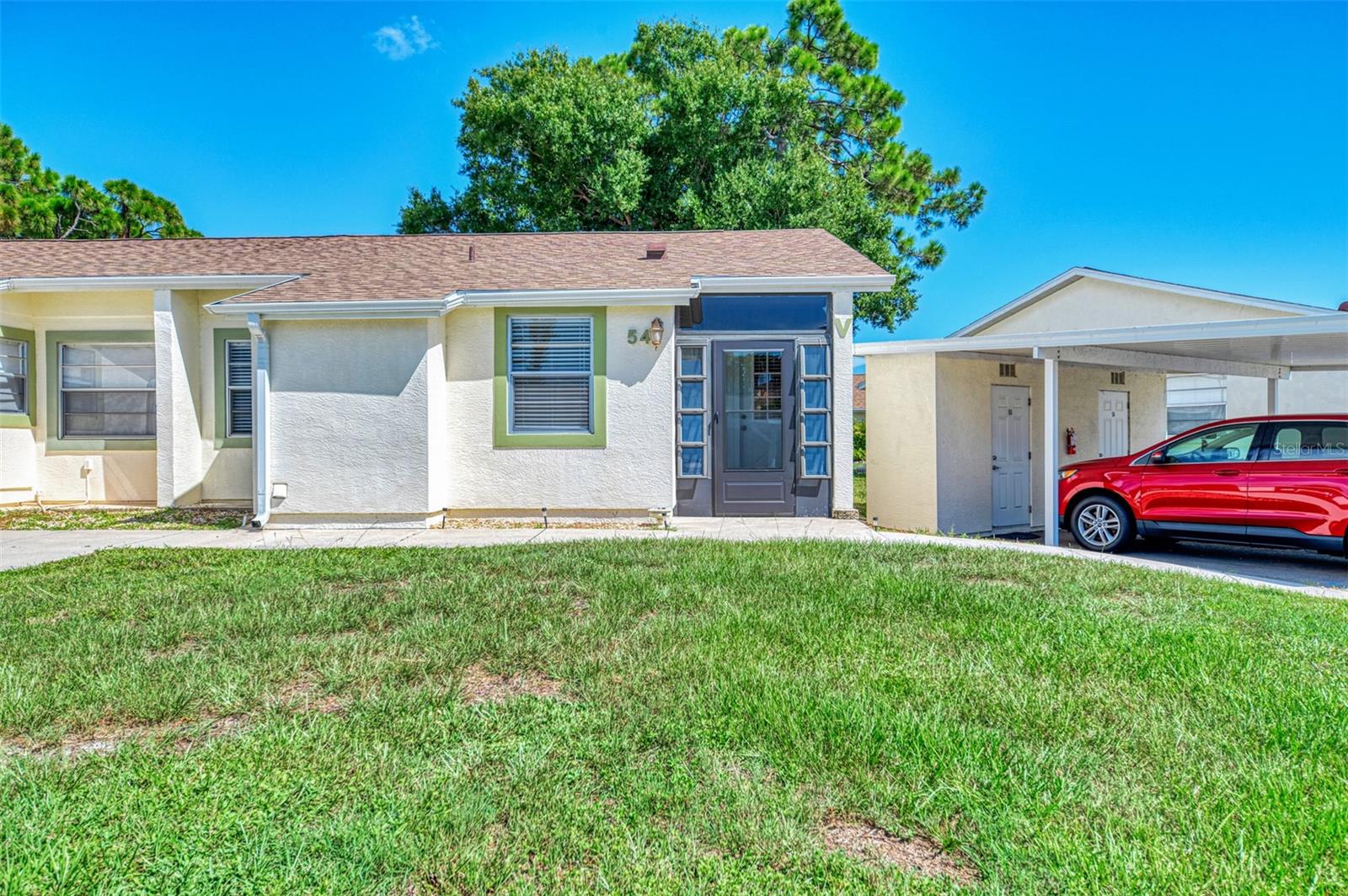 Enjoy peaceful views and easy Florida living in this well-maintained 2-bedroom, 2-bath first-floor condo in the desirable Village at Wildflower community. The bright, open layout features vaulted ceilings and wood-look laminate flooring throughout the main living areas and bedrooms. Relax in the enclosed Florida Room overlooking beautiful florida landscape—perfect for morning coffee or evening unwinding. Impact-resistant windows throughout and a newer Florida Room door provide added peace of mind. The primary suite offers a walk-in closet and private bath, while the split-bedroom layout provides privacy for guests. A dedicated utility room with washer and dryer adds convenience. Enjoy a community pool, maintained grounds, and assigned covered parking, all just minutes from Gulf beaches, shopping, dining, golf, and medical facilities. A wonderful choice for year-round living or a seasonal Florida retreat.