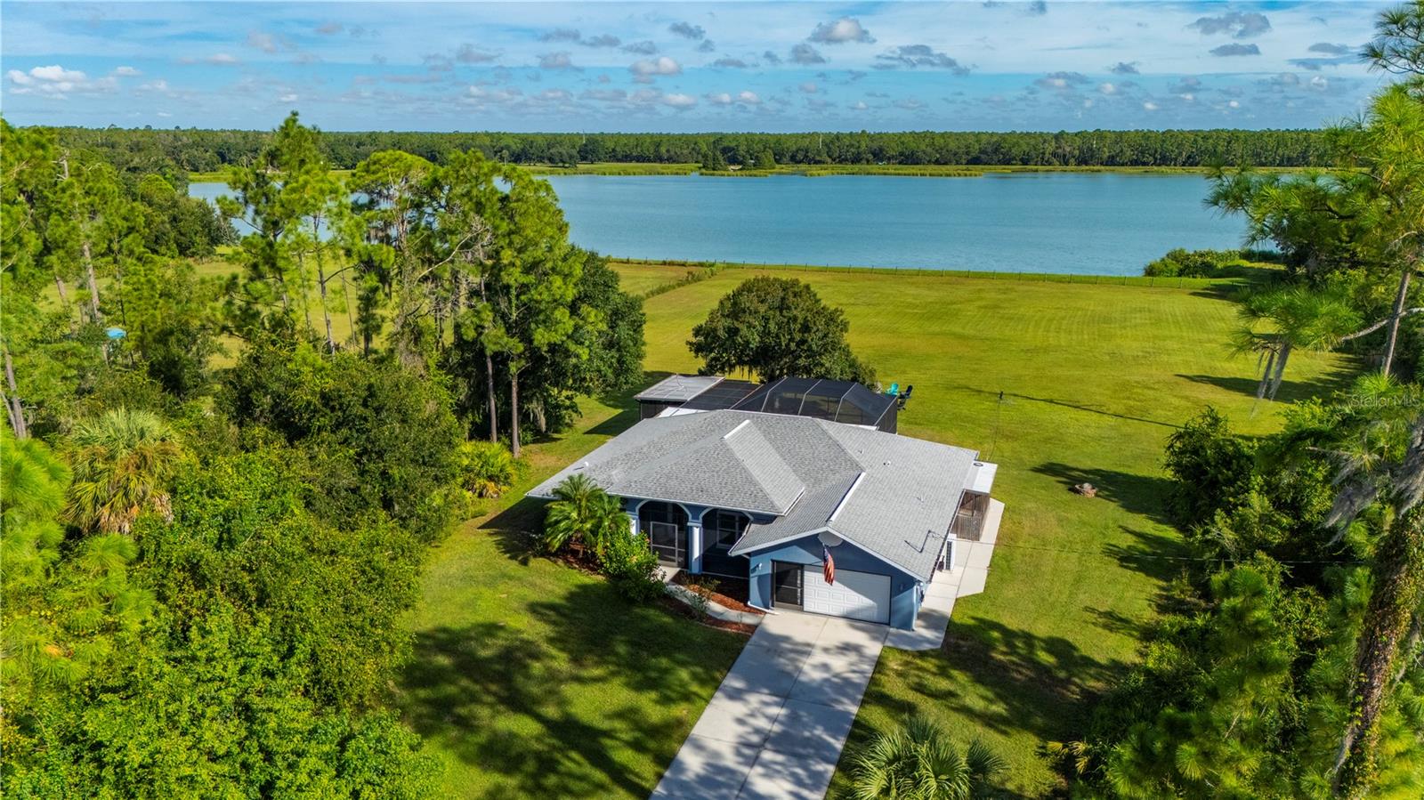 Virtually Staged. 4 Acres | 249 Ft Lakefront | Horses Allowed | AG Zoned | No HOA or CDD

This 4-acre waterfront property is fully fenced, with 249 feet of frontage with a view of Lake Cosmic, one of the largest lake views in the area, and unobstructed views across the water. Only 16 properties share this view. This completely updated pool home in Terra Del Sol, North Port, is zoned AG with horses and livestock allowed, making it a strong option for buyers looking for horse property. Approximately 2 acres are cleared, and a long, tree-lined driveway sets the home well back from the road.

The 3-bedroom, 2-bath concrete block home has a bright, open split floor plan with high ceilings, plank-style tile, and plantation shutters throughout. It offers 1,891 sq ft of living space plus a 290 sq ft air-conditioned Florida room overlooking the lake, for 2,181 sq ft under air and 3,196 total sq ft. The kitchen is made for cooking. It spans roughly 25 feet with granite counters throughout, an oversized island with a sink, stainless steel appliances, and tall pantry cabinets. A separate L-shaped prep counter gives you a second workspace that looks out to the pool and lake. The primary suite has a custom walk-in closet and a modern bath with subway tile, dual sinks, a freestanding soaking tub, and a glass-enclosed walk-in shower. A screened front porch and a two-car garage with epoxy floors complete the home.

Outside, the screened lanai covers over 1,800 sq ft and faces the lake. It has a covered seating area with Mexican tile, a heated saltwater pool, and an outdoor kitchen with a built-in gas grill, burner, and sink. Mornings with coffee overlooking the water, afternoons in the pool, and evenings around the fire pit come with the property, along with room on the acreage for horses, gardens, and projects.

The 1,500 sq ft detached metal building, built in 2014, includes an air-conditioned shop of about 1,200 sq ft and a 300 sq ft covered equipment bay. The shop has 10-foot doors, 18-foot ceilings, electricity, plumbing, a full bath, and two levels of storage. It's ready for an RV, boats, equipment, or a workshop. A separate RV electric hookup is also on the property.

Updates include A/C (2024), impact windows (2021), roof (2019), and a tankless water heater. The property is in flood zone X, outside FEMA's special flood hazard area.

It's country living in Sarasota County with everything close by: I-75, Wellen Park, Braves spring training, beaches, healthcare, schools, places of worship, shopping, and dining.