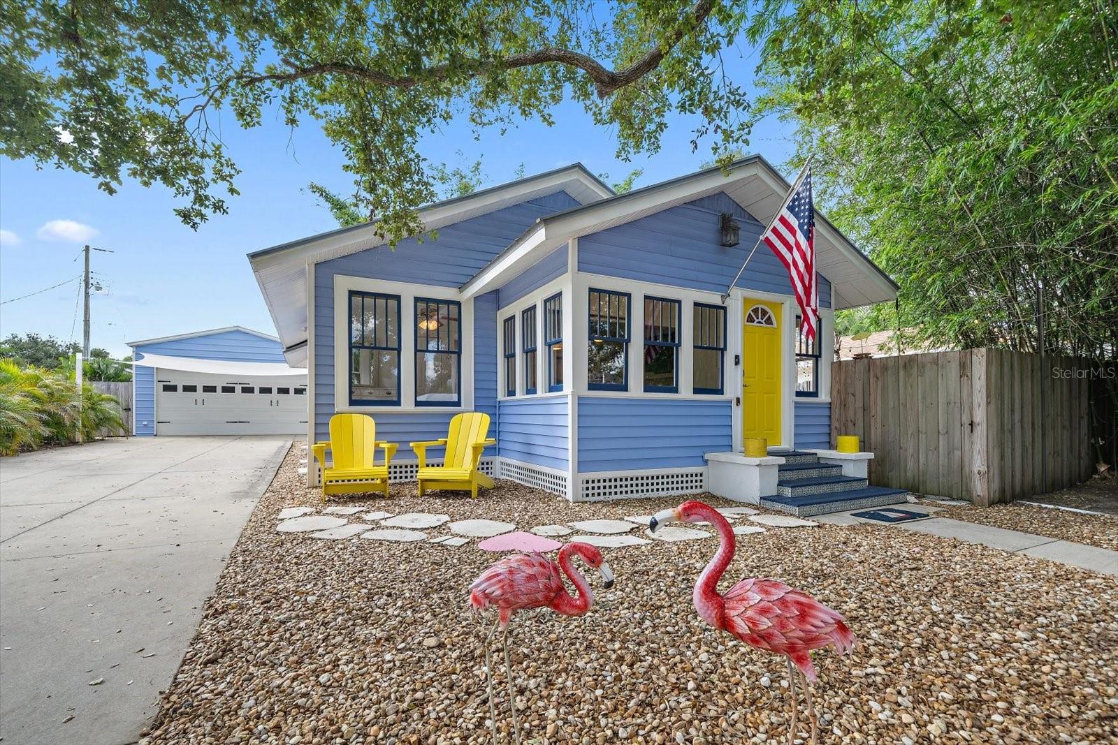 Welcome to this charming Sarasota bungalow filled with character and thoughtful upgrades! The inviting exterior features coastal blue siding, a cheerful yellow front door, and low-maintenance landscaping. Inside, enjoy new laminate flooring, a bright enclosed sunroom, living room with brick fireplace, dining area with built-in cabinetry, and kitchen featuring granite countertops, white cabinetry, and stainless steel appliances. A unique bonus entertaining space showcases exposed wood beams, decorative lighting, and a built-in bar. Outside, enjoy a fenced yard, tropical landscaping, and private outdoor shower! Major improvements include updated electrical and plumbing, a double-wide driveway, new fencing, and upgraded attic insulation with radiant barrier for improved energy efficiency and potential utility savings. The impressive 600 sq. ft. detached garage with adjoining carport features insulated walls, 60-amp electrical service, polyurea flooring, and an oversized hurricane-rated garage door. Conveniently located near Arlington Park, Southside Village, Sarasota Memorial Hospital, downtown Sarasota, shopping, dining, and Siesta Key Beach!