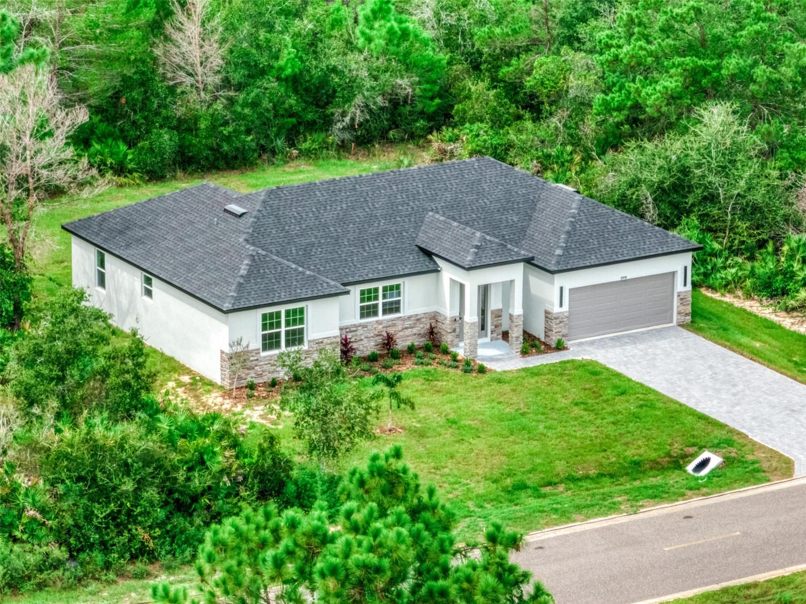 NEW CONSTRUCTION meets elevated design and exceptional craftsmanship in this stunning concrete-block 3-bedroom, 3-bath home with a 2-car garage in sought-after Sun ’N Lake of Sebring. From the moment you arrive, the impressive stone-accented façade and 8' entry doors set the tone for the quality found throughout. Step inside to soaring 10'+ ceilings with multiple tray details, wide-plank waterproof flooring, and a custom designer wood-paneled feature wall with an inset electric fireplace and dedicated space for a wall-mounted TV. At the heart of the home is a beautifully designed kitchen featuring thick waterfall quartz countertops, a generously sized island, abundant cabinetry, and pantry storage. The spacious living room flows seamlessly into the kitchen and dining areas, creating an open and inviting layout ideal for both everyday living and entertaining. Every bedroom offers a walk-in closet, while the generously sized guest bedrooms measure approximately 13'x12'. One guest suite includes its own private bathroom with a stylish low-threshold walk-in shower—perfect for family or overnight guests. Throughout the bathrooms, floor-to-ceiling tile, designer mirrors, and carefully selected finishes showcase the attention to detail invested in this home. The 15'x14' primary suite is a true retreat, complete with an 8'x6' walk-in closet and an extraordinary 15'x13' spa-inspired bathroom. Its showpiece is the oversized glass-enclosed shower and soaking-tub combination, surrounded by beautiful large-format tile extending to the ceiling. Dual sinks and a private water closet complete this impressive space. Additional features include an indoor laundry room and a custom landing station with matching cabinetry near the garage entrance—ideal as a coffee bar, drop zone, mail station, or morning prep area. Outside, well irrigation is already installed to maintain the landscaping, while the large, flat backyard provides plenty of room for recreation, entertaining, or creating your own outdoor retreat. Located in desirable Sun ’N Lake of Sebring, the community offers golf courses, 24-hour security patrols, nature trails, a community center and pool, restaurants, and golf-cart-friendly living. A HOME WARRANTY is included, and potential lender assistance may be available. Schedule your private showing today or ask about the 3D Virtual Home Tour!