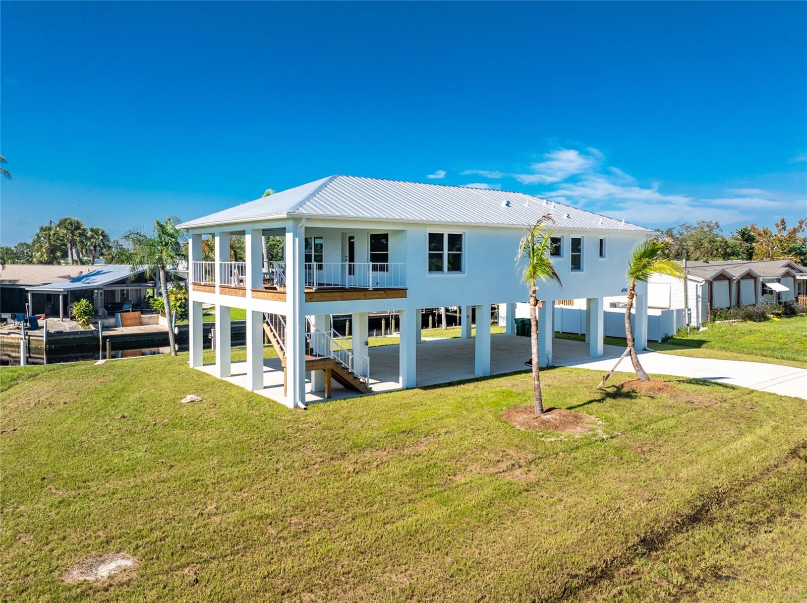 YOUR GULF-ACCESS PARADISE AWAITS! NO BRIDGES. ELEVATED 8'3" ABOVE REQUIRED FLOOD ELEVATION. METAL ROOF. IMPACT WINDOWS & DOORS. LUXURY COASTAL LIVING.

Imagine stepping into a life where spontaneous boating adventures, spectacular sunsets, and the beauty of Southwest Florida are part of your everyday routine. This newly constructed waterfront gem delivers the coastal lifestyle buyers dream about, combining Gulf , home is  built on concrete stilts and has been elevated 8’.3” above the required flood elevation, long lasting metal roof for an exceptional combination of lifestyle and desirable construction features. Set on a quiet street with water views, this beautifully designed 3-bedroom, 2-bath residence pairs sophisticated coastal finishes with the freedom of waterfront living.

From the moment you step inside, you'll appreciate the thoughtfully curated palette of soft neutrals, subtle coastal hues, and designer details that create an atmosphere of relaxed luxury. The stunning kitchen is a showstopper, featuring gorgeous quartz countertops with delicate blue-green and gray veining, an expansive island ideal for entertaining, upgraded appliances, and an elegant glass backsplash with just a hint of coastal color. Beautiful coastal lighting and carefully selected finishes bring the entire space together in effortless style.

Water-resistant luxury vinyl flooring flows throughout, combining beauty with everyday practicality. The primary suite offers a spa-inspired retreat with a beautifully tiled walk-in shower, glass doors, pebble-stone flooring, and dual vanities. The guest bathroom continues the coastal aesthetic with its own thoughtfully selected tile finishes.

Extend your living space outdoors to the spacious covered lanai, perfect for morning coffee, alfresco dining, and relaxing in the warm Florida breeze. Below, the expansive covered area provides generous parking and storage for vehicles, boats, and recreational gear. Impact-resistant windows and doors add protection and energy efficiency, while the concrete seawall and dock equipped with water and electricity make waterfront living even more convenient. With no bridges to navigate on your way to the Gulf, your next fishing trip, diving, island adventure, or sunset cruise is always within reach.

Just minutes from beautiful beaches, scenic parks, fishing and kayaking destinations, shopping, dining, and everyday conveniences, this property offers an exceptional blend of luxury, location, and lifestyle. Beautifully decorated and available with optional furniture, it presents an enticing opportunity as a full-time residence, seasonal escape, or private coastal retreat.

Don't just dream about the Southwest Florida lifestyle—come live it! Discover the freedom of Gulf access, the appeal of elevated construction, and the beauty of designer coastal living in one remarkable waterfront home.

Additional information: The home is designed to accommodate a future lift installation, if desired. Although the home is elevated above the required flood elevation, some insurance companies may still require flood insurance. Buyers should verify flood insurance requirements. Survey and Elevation Cert. is available
