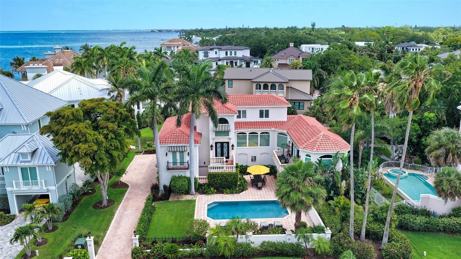 Sophisticated gated living just moments from the heart of downtown Sarasota. Evoking the timeless elegance of Palm Beach with the warmth of Old Florida charm, this exceptional Spanish Mediterranean residence is tucked within the exclusive gated waterfront enclave of Tocobaga Bay. One of only 9 private residences in the community, ideally positioned just moments from Sarasota's renowned dining, arts, shopping and waterfront attractions. Surrounded by lush tropical landscaping and tranquil water views, the home is thoughtfully designed for both sophisticated entertaining and relaxed everyday living. Expansive interiors are filled with natural light, highlighted by a grand foyer, travertine flooring, oversized floor-to-ceiling picture windows, motorized shades, and custom window treatments throughout. The residence features 3 bedrooms, each with its own en-suite bath, along with a media room or private office and a private 3-stop elevator. The oversized 4-car garage offers exceptional storage and ample spaces for vehicles, golf carts, kayaks, and recreational equipment, while the air-conditioned bonus room appointed with premium finishes including a La Cornue gas cooktop, Sub-Zero refrigerator, custom Campbell Cabinetry, spacious walk-in pantry, oversized center island and Taj Mahal quartz countertops and backsplash. The oversized living room offers an inviting atmosphere for gathering, while the separate formal dining room is perfectly suited for elegant dinners and entertaining. The primary suite serves as a peaceful sanctuary complete with its own Juliette balcony, dual custom walk-in closets, and a spacious en-suite bath. Two additional guest suites occupy the third floor, each with private baths, offering ideal comfort and separation for family and guest. Designed to embrace Sarasota's indoor-outdoor lifestyle, the open-air heated saltwater pool is surrounded by lush tropical landscaping and expansive patio space for lounging and dining. Additional improvements: new tile roof (2023), new irrigation system (2024), updated water heaters (2023 & 2024), electrical panels (2024), and updated A/C units. Residents enjoy access to the community day dock with direct bay access, perfect for boating and waterfront enjoyment. Perfectly located near Sarasota's renowned beaches, St. Armanda Circle, The Bay Park, and the iconic Ringling Bridge, this remarkable residence offers an exceptional lifestyle just minutes from the energy and culture of downtown Sarasota. Offered fully furnished and ready for immediate enjoyment.