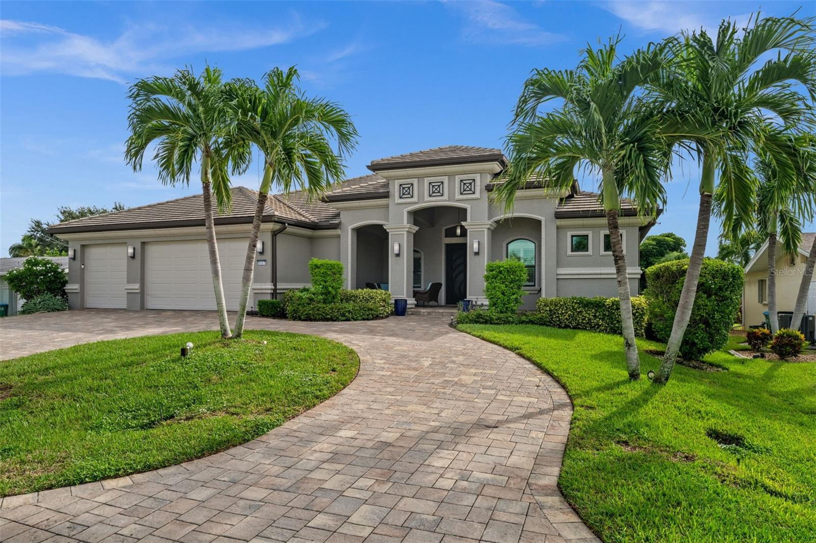 DIRECT GULF ACCESS IN CAPE CORAL’S FAMOUS YACHT CLUB AREA. JUST MINUTES TO OPEN WATER WITH NO BRIDGES! This custom-built 4-bedroom, 3-bath home offers 2,883 square feet of beautifully designed living space and is truly made for entertaining. From the paver circle driveway, mature tropical landscaping and striking custom steel-and-glass entry doors, this home makes an impressive first impression. Inside, the huge open great room features soaring tray ceilings, crown molding and dramatic 90-degree zero-corner sliding doors that open the home to the lanai and pool. The spacious kitchen is designed for gathering, with granite countertops, glass tile backsplash, stainless appliances, glass cooktop, wall oven, stainless vent hood, center island, walk-in pantry and an oversized breakfast bar with plenty of room for family and guests. A separate wet bar with wine cooler adds even more entertaining space. At the rear of the home, a comfortable family room overlooks the pool and canal and can easily serve as a media room, TV room or quiet retreat. The large primary suite has direct access to the lanai and features walk-in closets, dual vanities, a soaking tub and a large walk-in shower. Outside is where the Florida lifestyle really comes together. The expansive screened lanai includes a heated pool, outdoor kitchen, bar and plenty of covered space for dining and relaxing. Boaters will love the dock with captain’s walk, covered boat lift and incredibly fast, bridge-free access to open water in less than five minutes. From here, it’s an easy boat ride to waterfront restaurants, beaches, the Caloosahatchee River and the Gulf. Additional features include hurricane-impact windows and doors, a modern tile roof and an oversized 3-car garage with extra room for a workshop or storage. The property has never flooded during any storm. A fantastic Yacht Club location, exceptional boating access and an entertaining-focused floor plan make this a standout Cape Coral waterfront home.