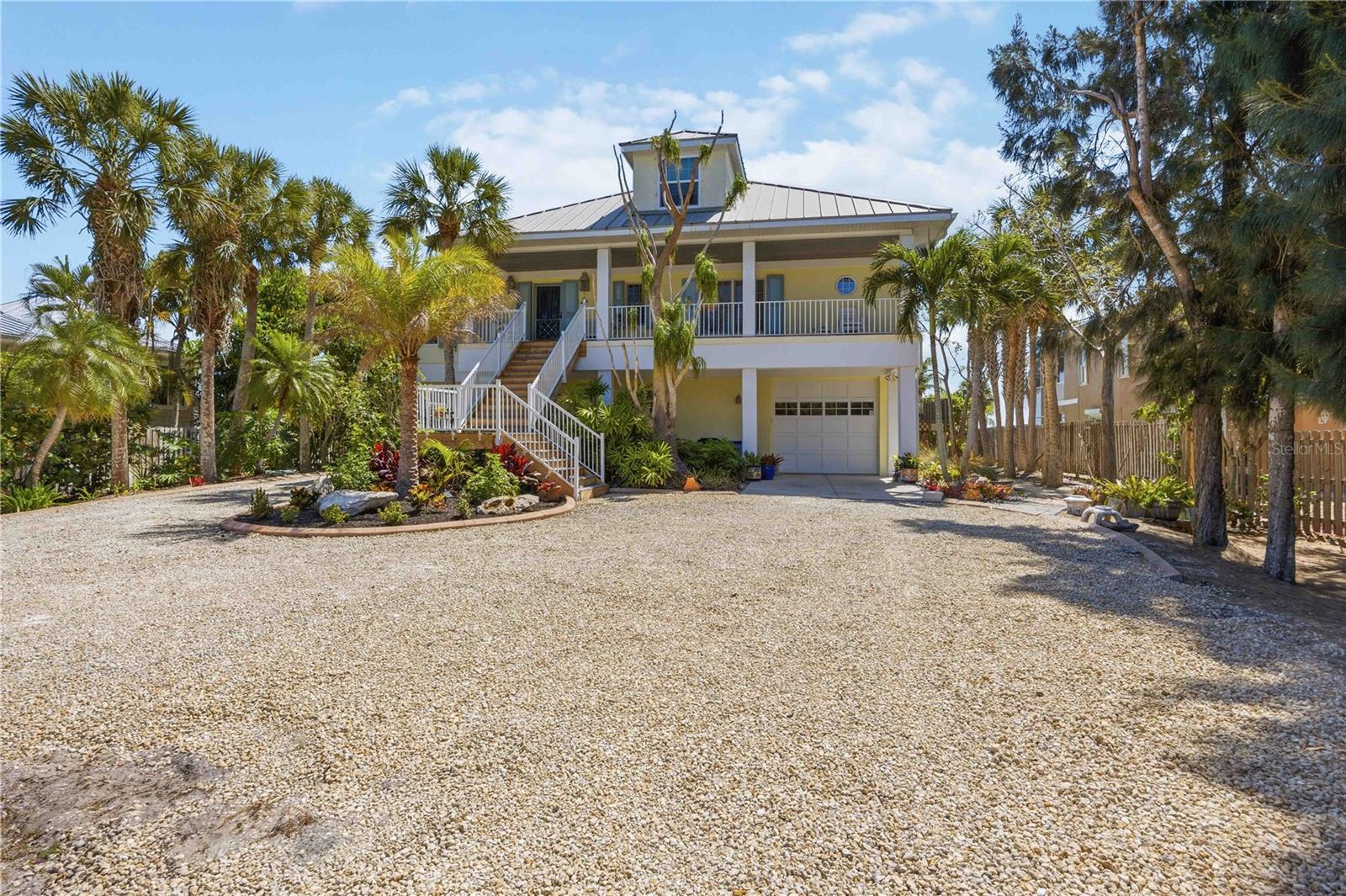 Welcome to one of the premier locations on Manasota Key, where nearly an acre of bayfront delivers picturesque views across the protected waters of Lemon Bay. A palm-lined private drive sets the tone for this custom-built 4-bedroom, 4-bath residence, designed to capture light and water from every angle.
Inside, soaring vaulted ceilings and walls of glass fill the open main level with natural light. The living room, dining area, and chef's kitchen — featuring premium appliances, natural quartzite countertops, and direct bay views — flow together and open onto a full-width screened balcony overlooking the pool, dock, and bay. The primary suite offers its own screened porch with panoramic vistas, plus a spa-like bath with dual vanities and an oversized walk-in shower. A flexible main-level guest room works equally well as an office or studio, while two upstairs suites with dormer windows and window-seat alcoves give family and guests private retreats.
Outside is pure resort living: a 40+ foot heated pool with full bath and outdoor shower, a brand-new deep-water dock (2025), private workshop, and a sandy shoreline perfect for kayaks and paddleboards. An elevator (2023) provides seamless access from the oversized 4-car garage — with room for boats, an RV, or toys — to the main living level. Best of all, deeded beach access puts the Gulf's sugar-sand shoreline just steps away.
Dolphins, manatees, and wading birds are daily visitors on this rare bay-to-Gulf property — a private slice of Manasota Key where waterfront living is at its finest.