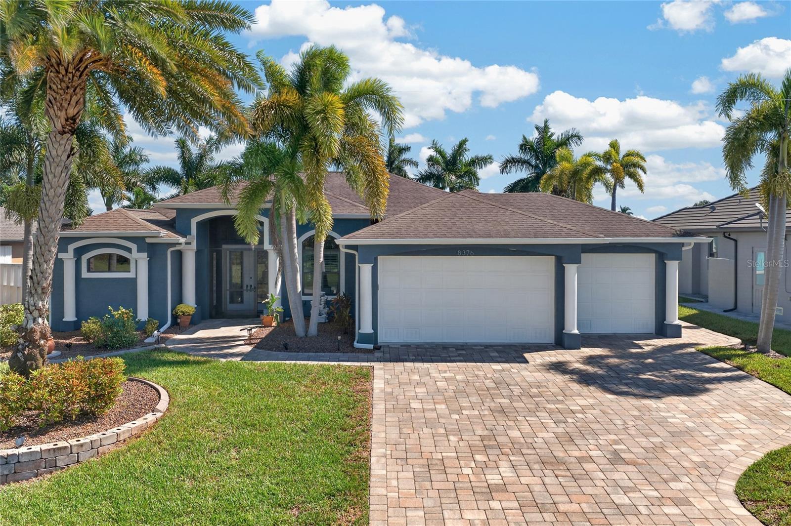 Welcome to 8376 Antwerp Circle, an exceptional 3-BEDROOM + OFFICE, 2-BATHROOM LUXURIOUS, WATERFRONT, SALTWATER POOL HOME WITH 16,000-LB BOAT LIFT nestled in the desirable boating community of SOUTH GULF COVE. Beautifully designed for both elegant entertaining and everyday comfort, this residence offers an impressive combination of architectural details, spacious living areas, and an extraordinary outdoor waterfront retreat. Boating enthusiasts will appreciate 80 FEET OF CONCRETE SEAWALL, an expansive 8' x 60' PRIVATE DOCK, a 16,000-LB BOAT LIFT, and convenient POWERBOAT ACCESS TO THE GULF through the South Gulf Cove lock system. A beautifully curved retaining wall enhances the waterfront setting, while a paver walkway leads to a charming canal-side fire pit area surrounded by tropical landscaping.

Step inside to discover SOARING CEILINGS, ELEGANT TRAY CEILINGS, CROWN MOLDING, and LUXURY VINYL PLANK FLOORING THROUGHOUT. The thoughtfully designed OPEN FLOOR PLAN creates a natural connection between the kitchen, dining, and living areas, with stunning canal views serving as the backdrop. A dramatic 90-DEGREE POCKET SLIDING GLASS DOOR opens the main living space to the expansive screened lanai, effortlessly blending indoor sophistication with outdoor Florida living. At the heart of the home, the beautifully appointed kitchen features GRANITE COUNTERTOPS, RICH WOOD CABINETRY, STAINLESS STEEL APPLIANCES, TILE BACKSPLASH, and an oversized center island ideal for gathering and entertaining.

The spacious PRIMARY SUITE offers a private sanctuary with an elegant tray ceiling, direct lanai access, and DUAL WALK-IN CLOSETS. Its luxurious en suite bathroom features DUAL VANITIES, AN OVERSIZED ROMAN SHOWER, and a DEEP SOAKING TUB designed for relaxation. Two generously sized guest bedrooms and a beautifully finished guest bathroom with a walk-in shower provide comfortable accommodations, while the DEDICATED OFFICE offers a versatile space for working from home or pursuing creative interests.

The true showpiece awaits outdoors! The EXPANSIVE SCREENED LANAI creates a private resort-style atmosphere, complete with a HEATED SALTWATER POOL, generous covered entertaining space, and a HOT TUB THAT CONVEYS WITH THE SALE. Spend your mornings overlooking the peaceful canal, afternoons cruising the waterways, and evenings unwinding beneath the Florida sky. Additional highlights include a NEW ELECTRICAL PANEL, ACCORDION HURRICANE SHUTTERS for the back lanai with METAL SHUTTERS for he rest of the home, A GENERATOR THAT CONVEYS, an indoor laundry room, and a spacious 3-CAR GARAGE.

Located in the waterfront community of SOUTH GULF COVE, with access to community parks, boating amenities, and nearby shopping, dining, golf courses, and Gulf Coast beaches, this remarkable home offers the perfect balance of luxury, recreation, and convenience. YOUR SOUTHWEST FLORIDA WATERFRONT LIFESTYLE STARTS HERE!