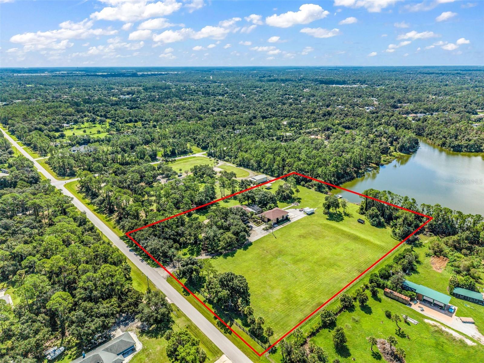 6 PRIVATE LAKEFRONT ACRES. GATED ENTRY. RV COMPATIBLE. RESORT-STYLE POOL. MASSIVE WORKSHOP. HIGH-SPEED FIBER INTERNET.

This is not your typical Florida property. Tucked behind a private Wi-Fi-controlled electric gate and surrounded by mature oak trees, this one-of-a-kind North Port estate delivers the space, privacy, and freedom that are nearly impossible to find this close to town.

The updated 3-bedroom, 2-bath home offers more than 2,600 sq. ft. of living space filled with character, including brick accents, granite countertops, plantation shutters, and warm, timeless finishes. A dedicated entertainment room with its own bar creates the perfect space for game days, movie nights, entertaining, or simply relaxing at home.

Outside is where this property truly sets itself apart. The resort-style pool features beautiful stone accents, cascading rock waterfalls, its own waterslide, and an expansive pool deck with plenty of room to entertain. Just beyond it sits a peaceful 21-acre spring-fed lake with your own private Trex dock. Kayak from the backyard, fish from the dock, enjoy coffee by the water, or watch the sunset beneath the mature oaks.

Bring the RV, boat, toys, and hobbies. This RV-compatible property gives you the acreage AND infrastructure to actually enjoy them at home. The impressive 2,400 sq. ft., two-story block and stucco workshop offers incredible space for storage, hobbies, recreational equipment, or a home business. Even better, the shop has its own separate 400-amp electrical service AND its own separate septic system, complete with an exterior access port for convenient RV hookup. It also includes approximately 375 sq. ft. of air-conditioned living or office space with its own bathroom, plus another 375 sq. ft. of finished space upstairs.

And you don't have to sacrifice connectivity for acreage. The property is serviced by high-speed fiber internet, making it easy to work from home, stream, run a business, or stay connected while enjoying the privacy of six acres.

The property offers even more possibilities with cleared, buildable land and Georgia clay fill already on site. Create additional living space, a guest house, barn, multigenerational setup, or simply keep the acreage open and enjoy the privacy.

Best of all, it feels like your own private escape without putting you in the middle of nowhere. You’re still minutes from shopping, dining, I-75, everyday conveniences, Sarasota Memorial Health Care System’s growing North Port presence, and even more development coming to the area, including a new Detwiler’s Farm Market planned near Sumter Boulevard and I-75.

If you’ve been looking for a property with room to live, play, entertain, build, work, and breathe without giving up the convenience of North Port, THIS is the one.