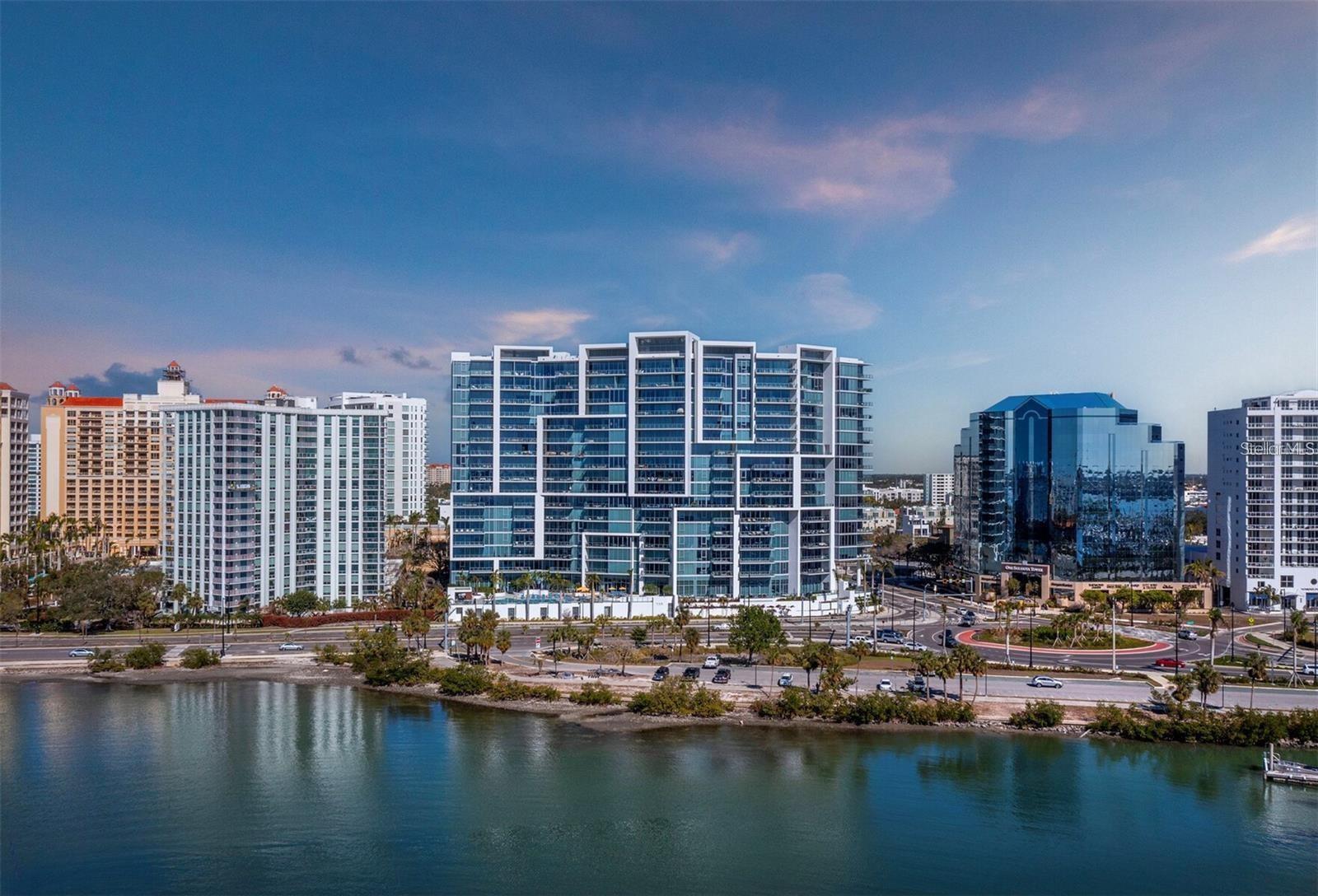 Numerous functional and design upgrades add significant value to this pristine, high-floor residence in one of Sarasota's most sought-after buildings. Positioned in a stack preferred for its through sight lines that showcase elevated vistas of both the waterfront and cityscape, this homes luxuries include large format porcelain tile flooring, motorized window coverings, premium custom cabinetry, custom built-ins in the living room and guest room, and designer lighting and fixtures throughout. With a layout ideal for entertaining and personal retreat, 1,770 A/C square feet encompass two large en-suite bedrooms as well as a separate den and powder bath and a dedicated utility and laundry room for added convenience. Private elevator access opens to a central vestibule and corridor that features spectacular, unobstructed views through floor-to-ceiling windows on either side of the residences. In the primary living space, the gourmet kitchen and dining area flow easily with the living room, all overlooking and opening fully to a deep private terrace with coveted southwestern exposure and marina views. Full-height windows and sliding glass doors create a seamless connection to the outside, expanding the living space with additional room for lounging and dining. Accentuated by a chic modern pendant, the dining area inside accommodates a table for six or more, with  adjacent counter seating at the oversized kitchen island. Arranged for optimal prep and hospitality, the kitchen features premium appliances and finishes including stainless double-door refrigerator, range and hood, wall oven, integrated microwave, and a deep basin sink. Bespoke cabinetry and surfaces complement the homes elevated modern style. Past the great room, the spacious owners suite enjoys exquisite west-facing views through a wall of glass, with room for seating, dual closets with custom built-in wardrobe systems, and a spa-like bathroom with a separate water closet, glass enclosed walk-in shower and an extra -long double vanity with cosmetic station. On the other side of the home, a large guest room enjoys an en-suite with soaker tub and floor-to-ceiling windows overlooking Downtown Sarasota. City views extend to the adjacent den, a generously sized flex space ideal for media lounge, private office, or occasional hospitality. Beyond the interior, this unit has the considerable advantage as one of only six in the building with a parking space that can be equipped for EV charging. Located within steps of the waterfront at the heart of Downtown Sarasota, VUE is renowned for its resort-style amenities and gleaming modern features. From the notable service amenities including valet and concierge to the heated pool and space with lounge areas, firepits, and grill station, and state-of-the-art fitness and resident lounges, this building offers a truly luxurious lifestyle. Furnishings available by separate offer for the ultimate convenience of turnkey acquisition.